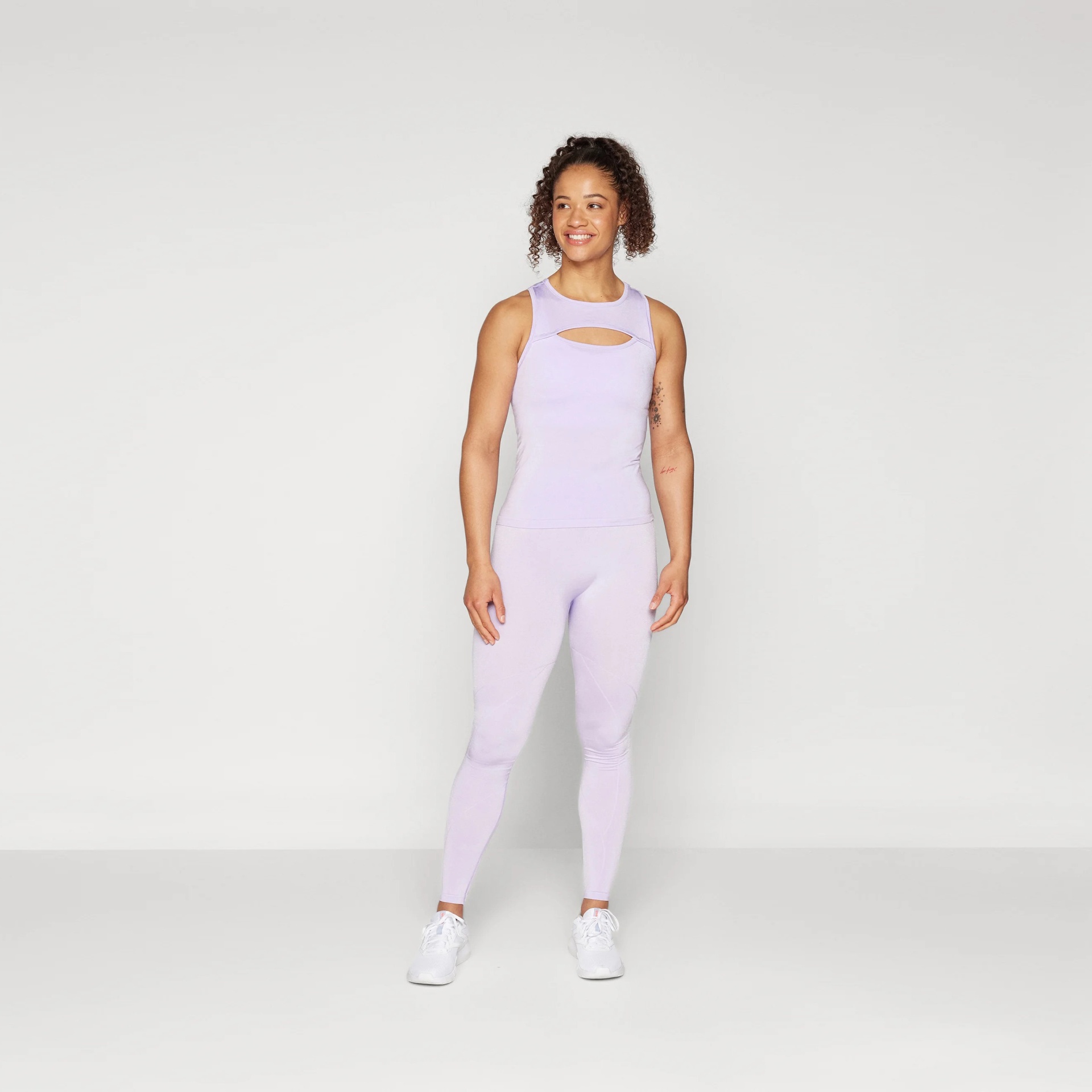 Conjunto de roupa desportiva lilás com top e leggings em modelo feminino