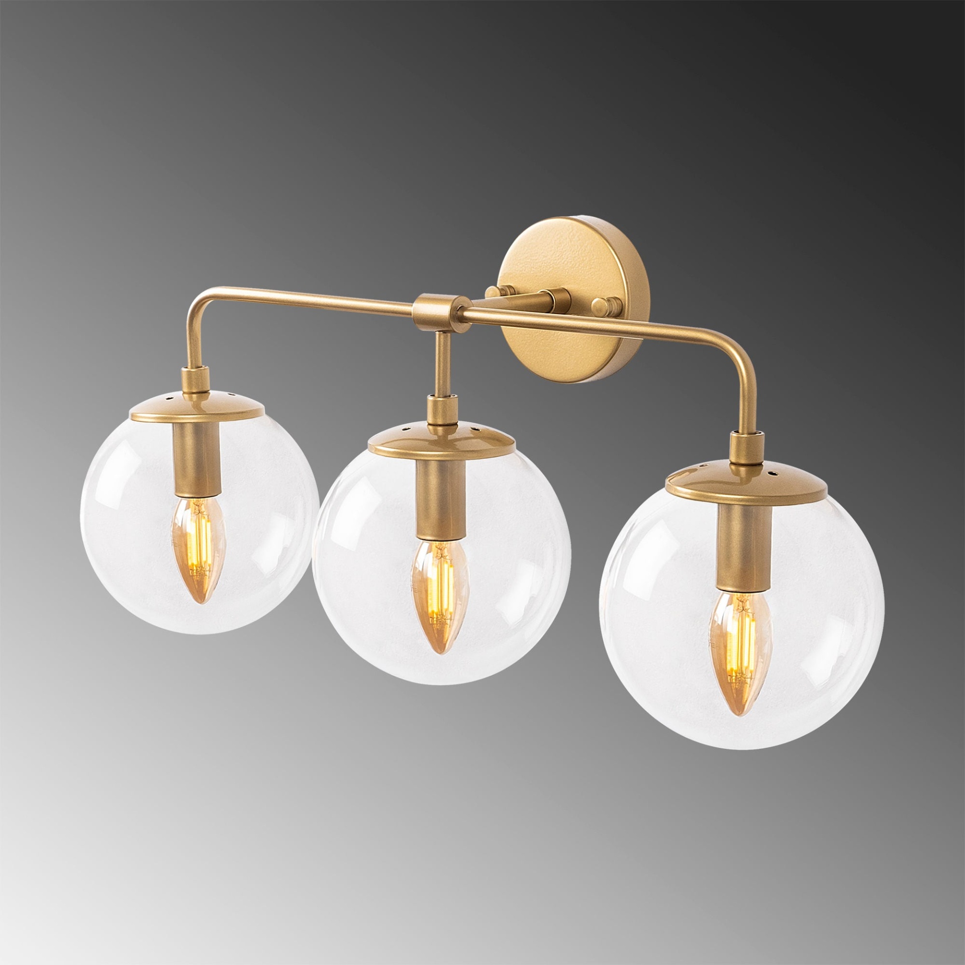 Candeeiro de parede dourado com três globos de vidro transparente