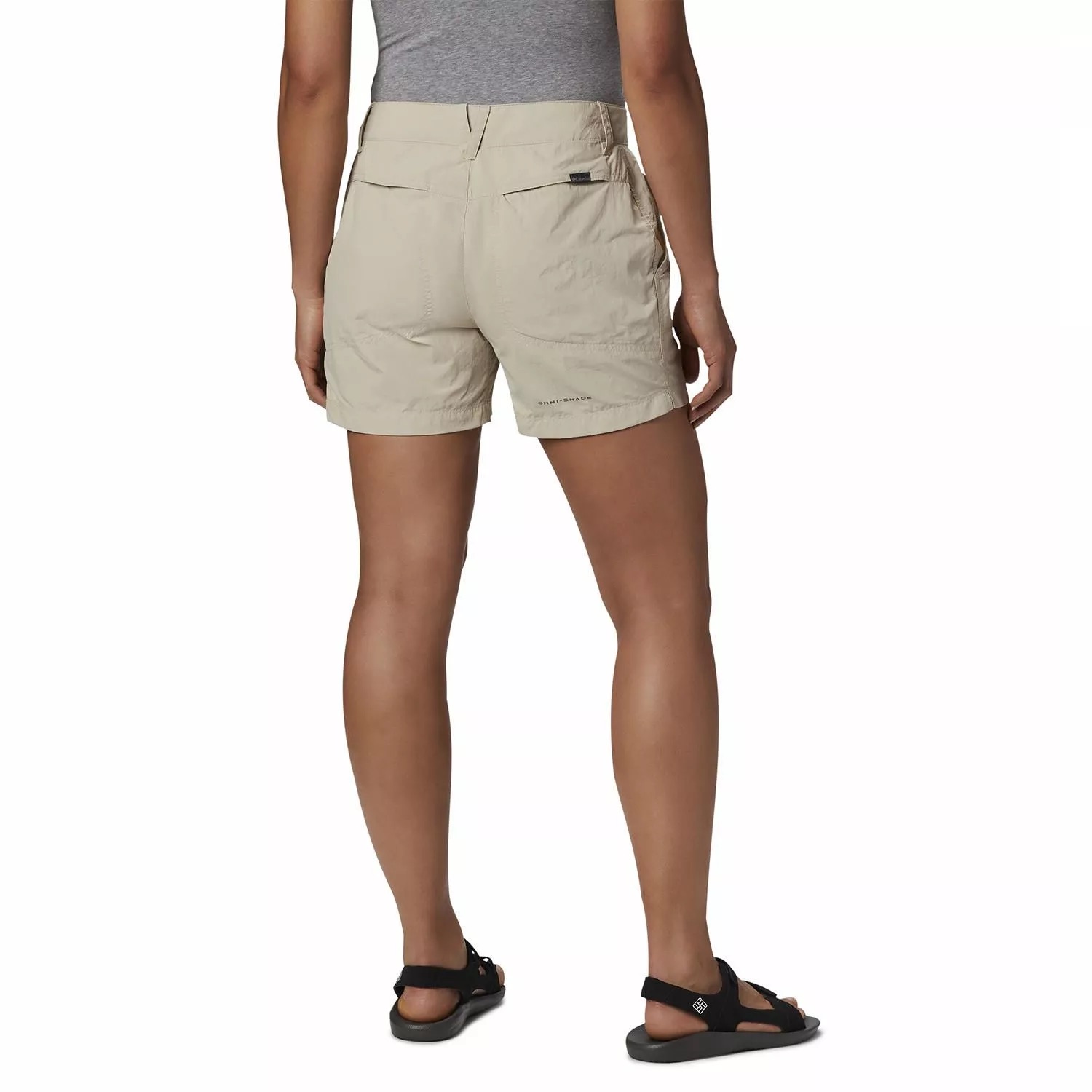 Shorts femininos bege claros com bolsos traseiros e etiqueta preta, usados por uma pessoa