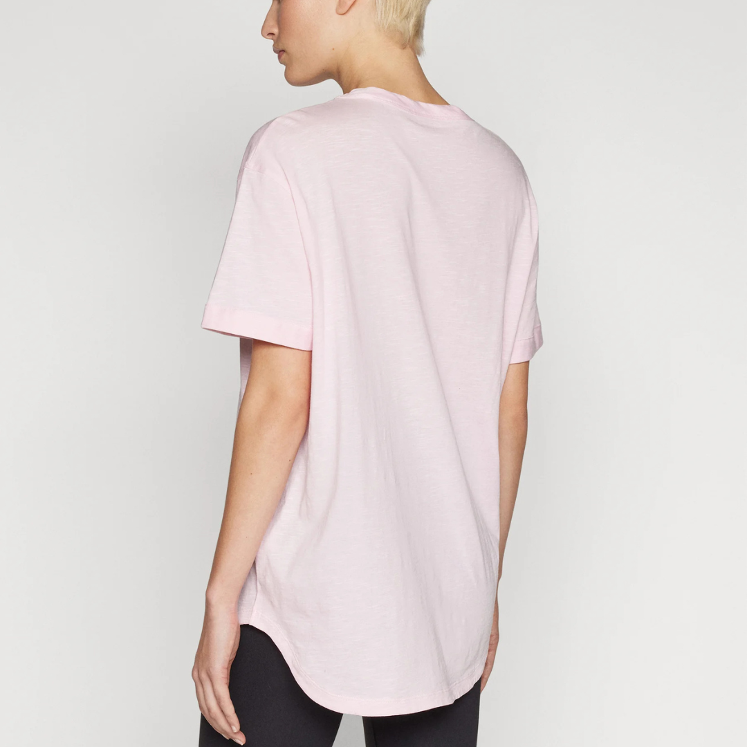 T-shirt rosa claro feminina vista de costas com leggings pretas