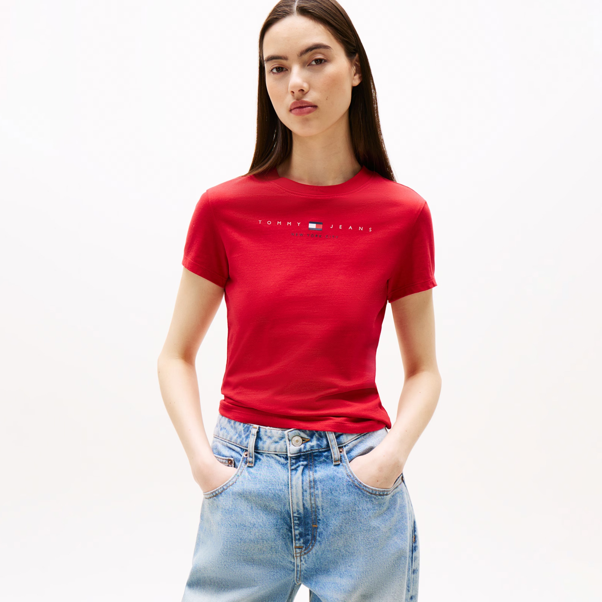 Mulher com camiseta vermelha Tommy Jeans e calças de ganga azuis