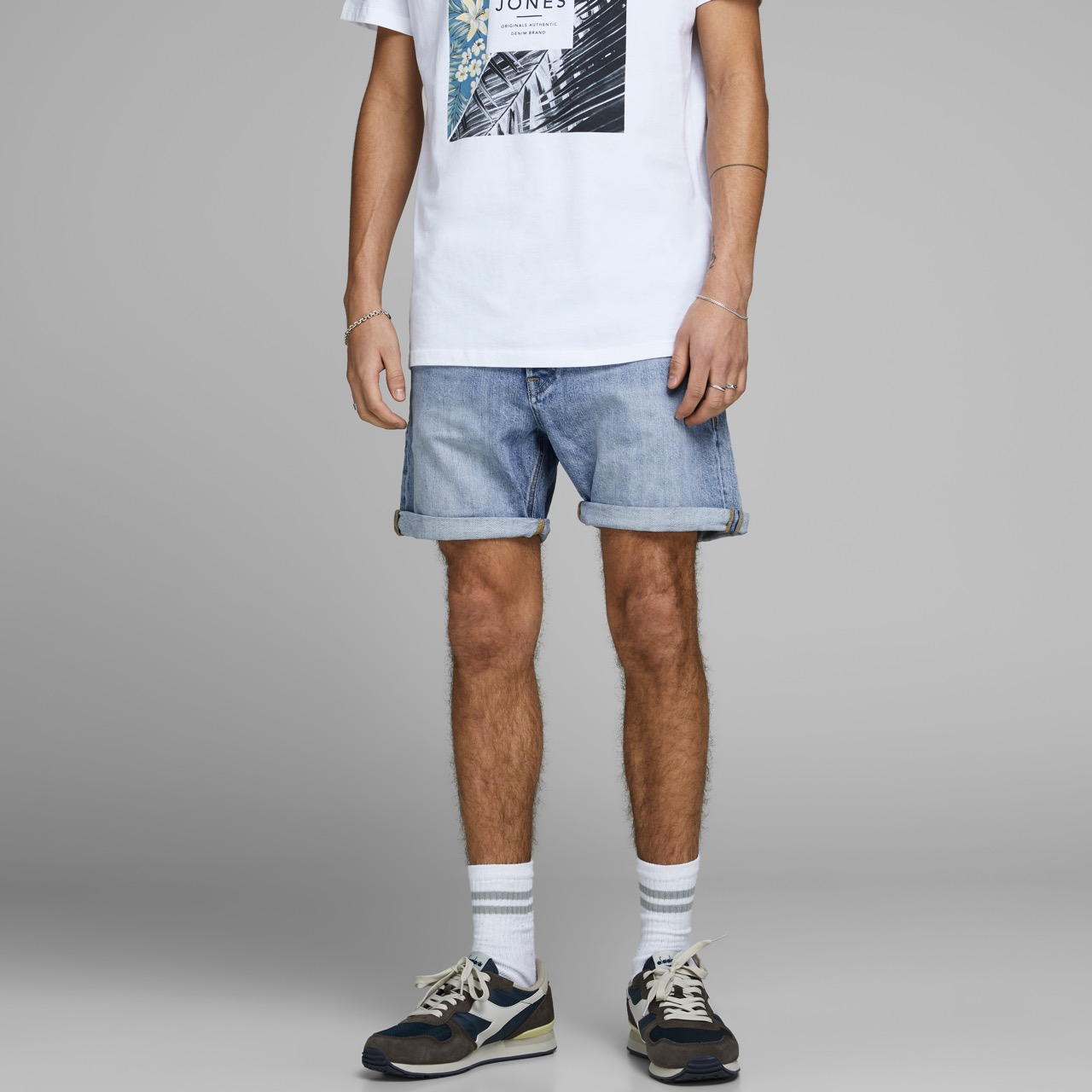 Homem de calças curtas de ganga, meias brancas com riscas e sapatilhas desportivas