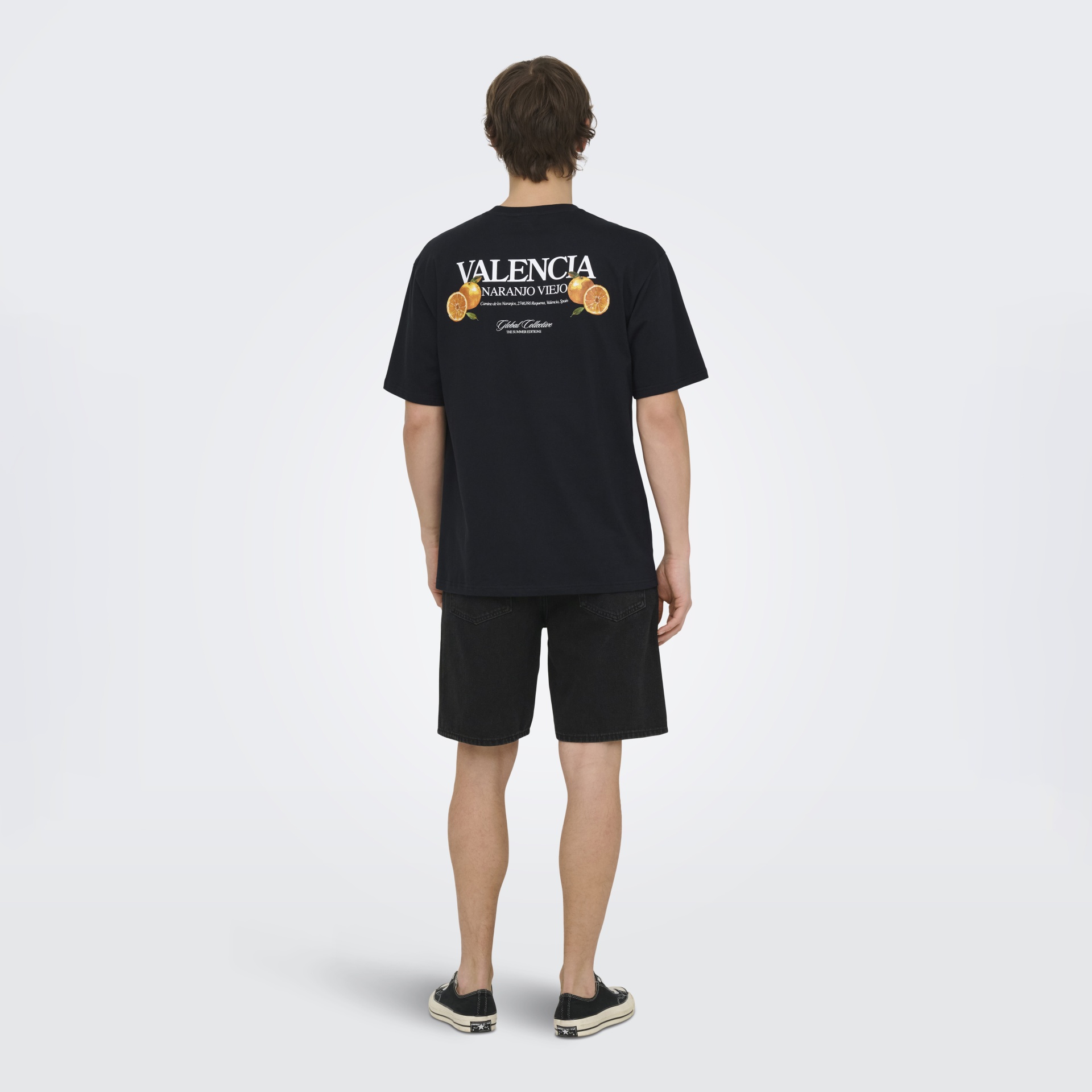 Pessoa de costas com t-shirt preta estampada e calções escuros
