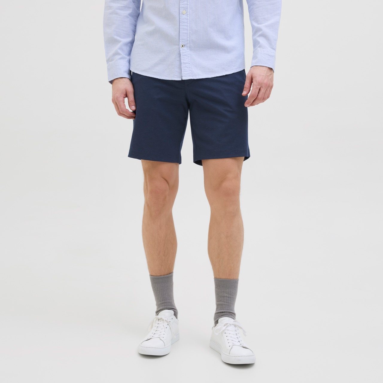 Calções masculinos azul escuro, meias cinzentas e sapatilhas brancas