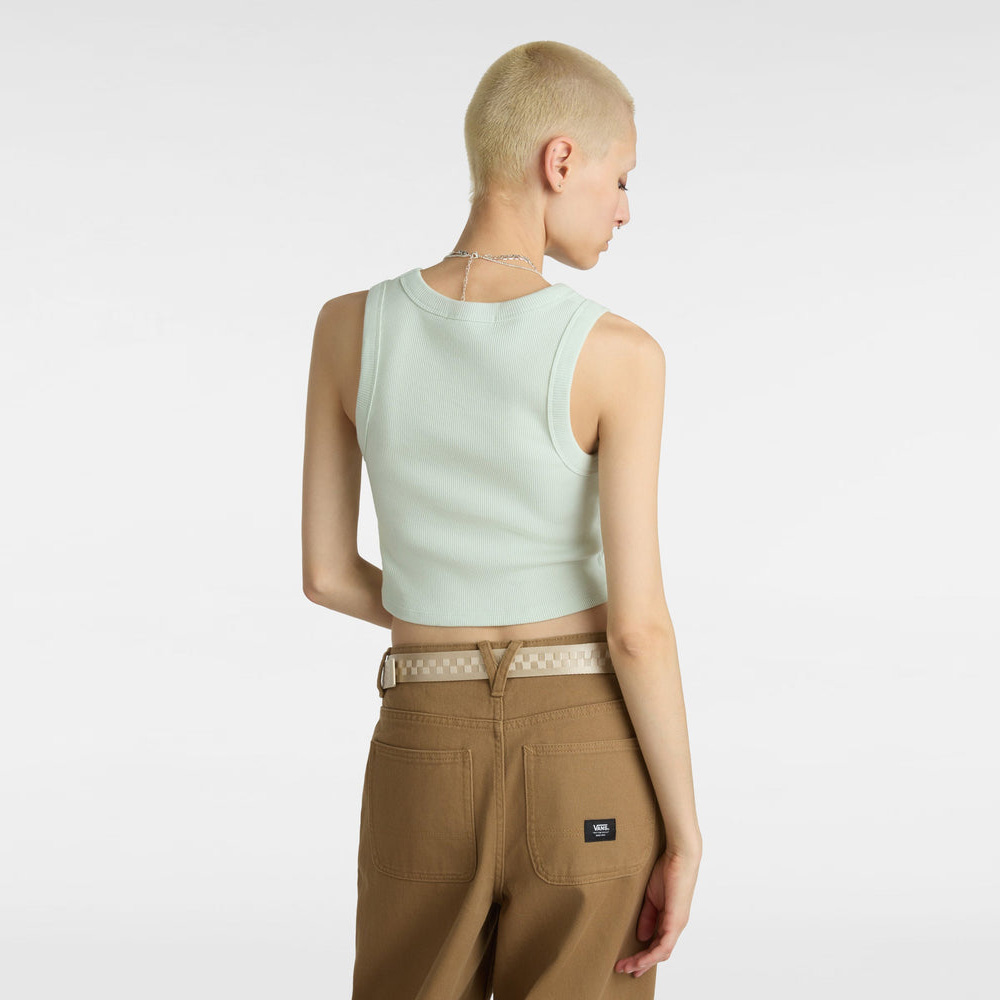 Mulher de costas usando top verde claro e calças castanhas com cinto bege