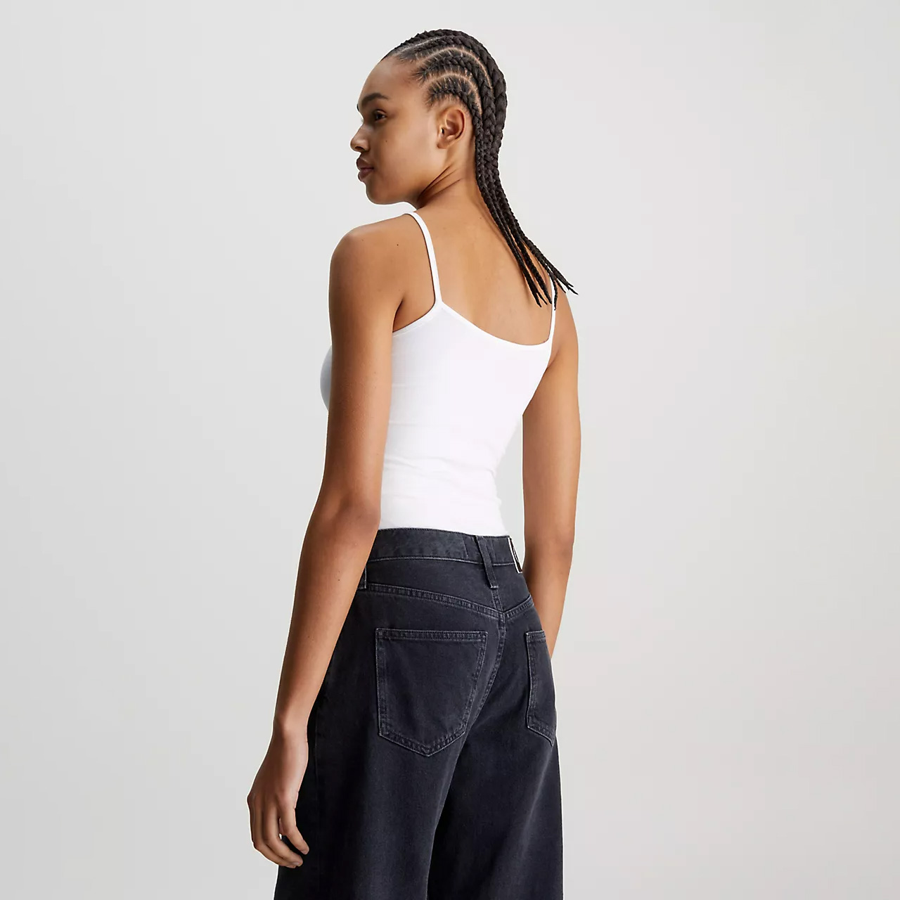 Mulher de costas com top branco e calças de ganga preto