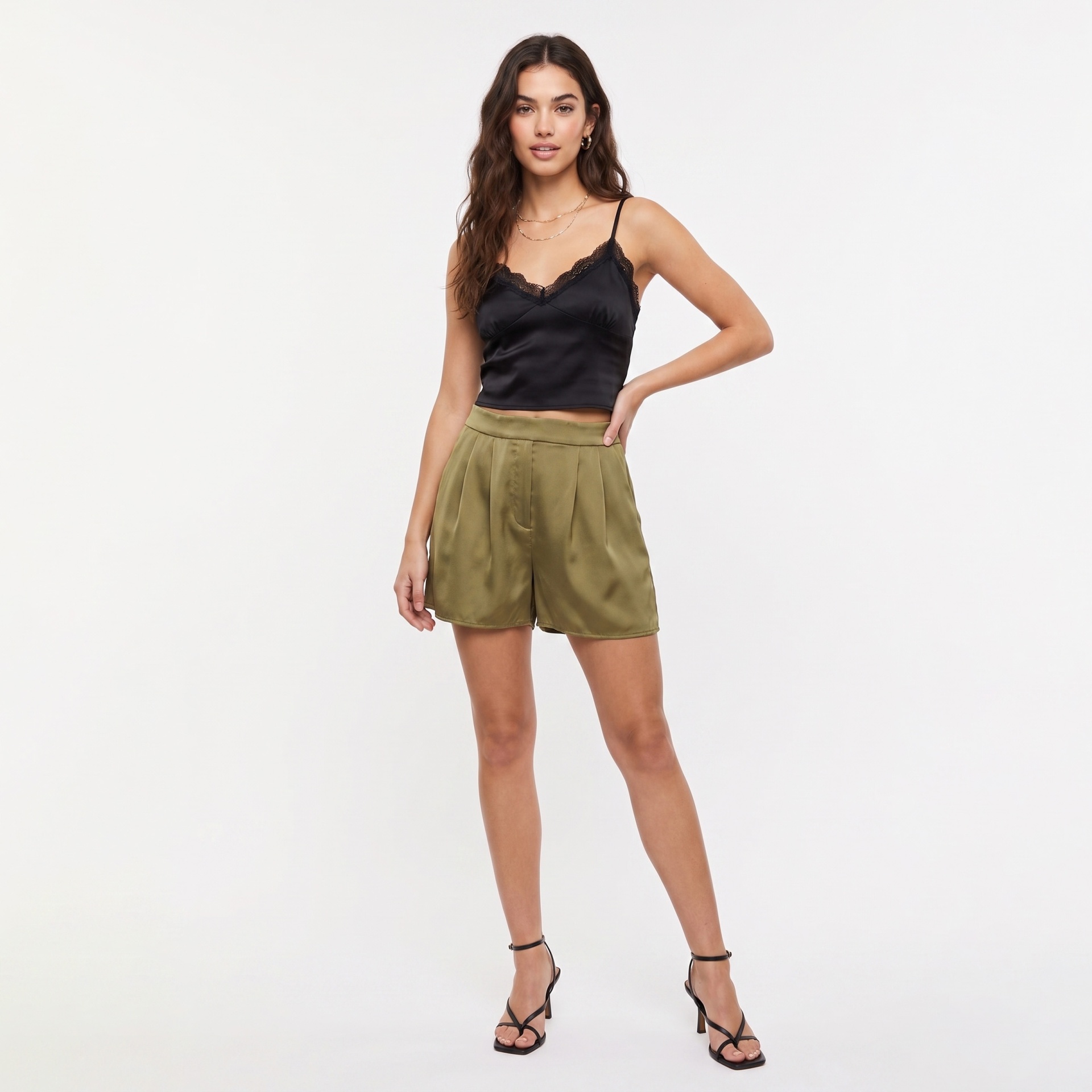 Mulher vestindo blusa preta com renda e calções verde-oliva em fundo branco