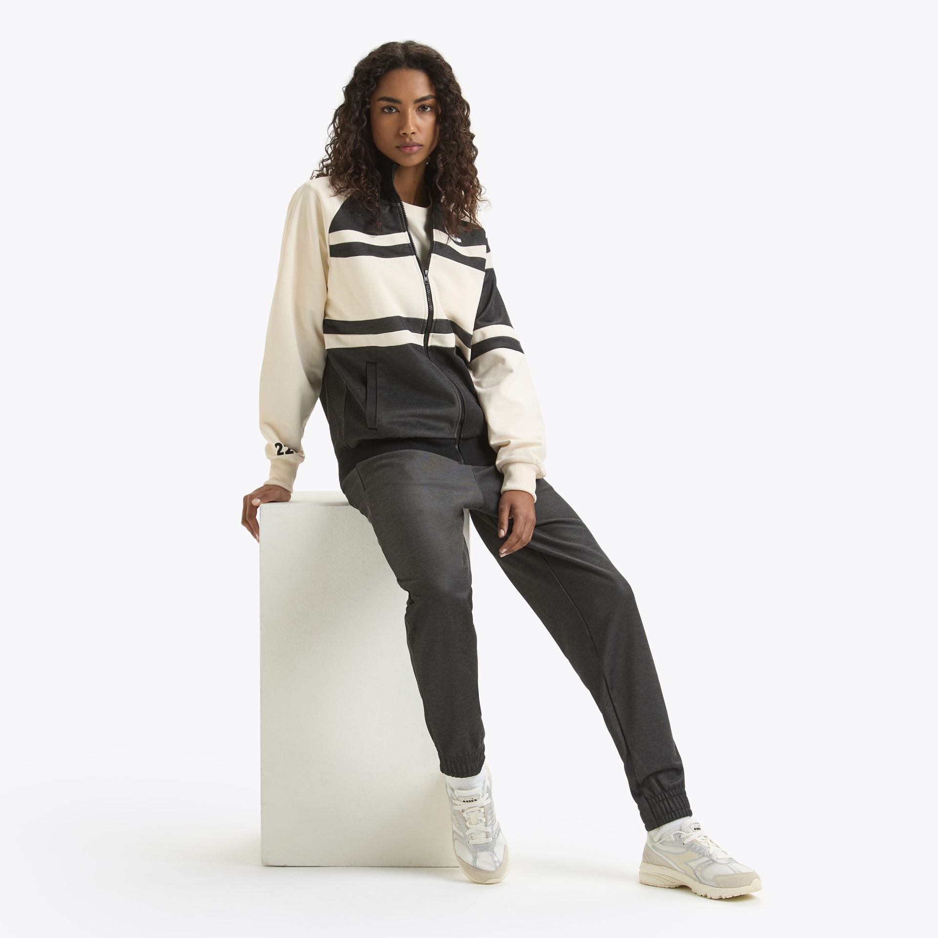 Conjunto de roupa desportiva preta, branca e bege com calçado desportivo branco