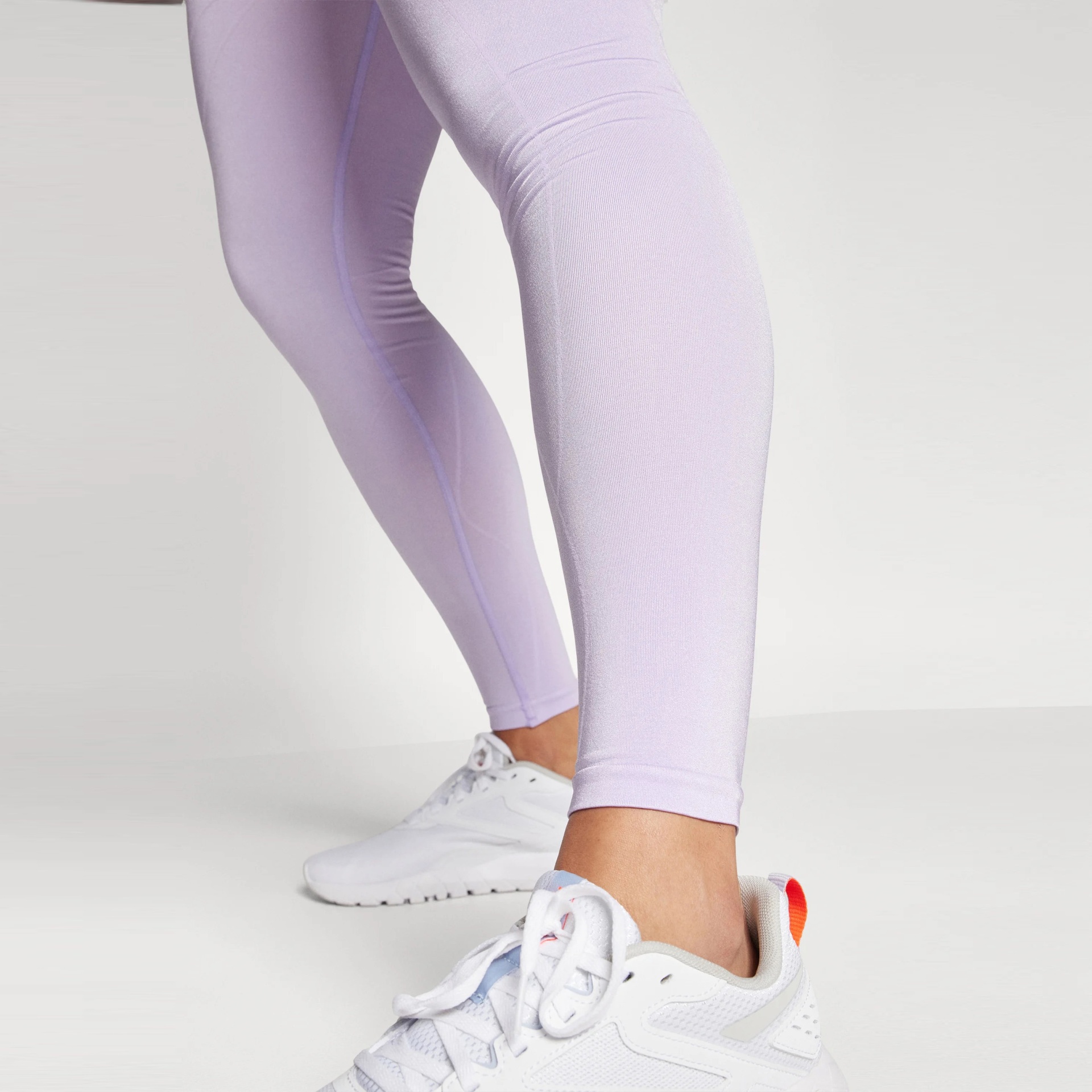 Leggings lilás com tênis branco e detalhes laranja