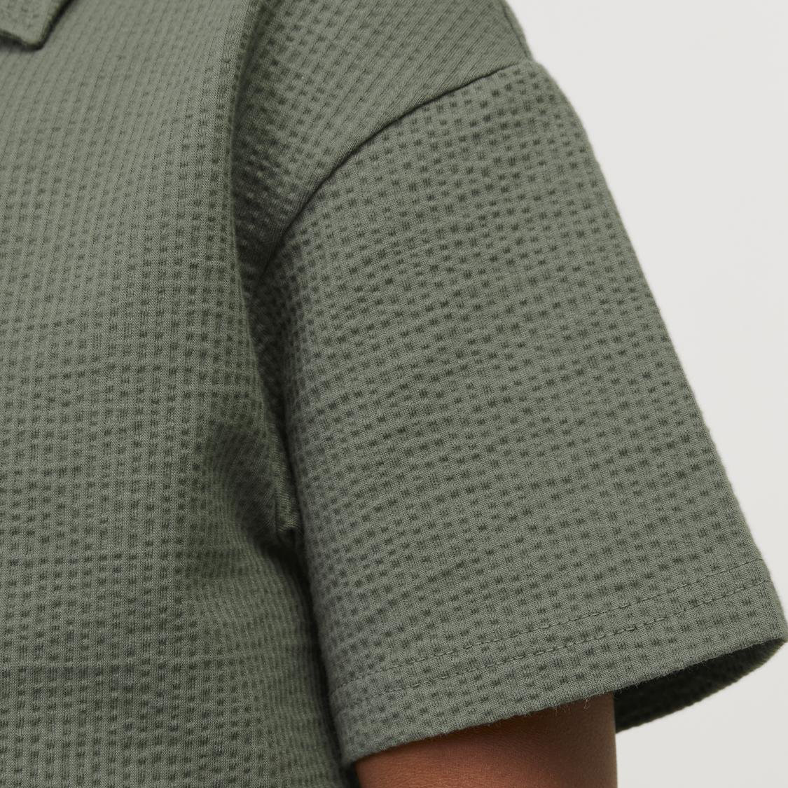 Manga curta de camisa ou t-shirt verde com padrão texturizado em quadrículas