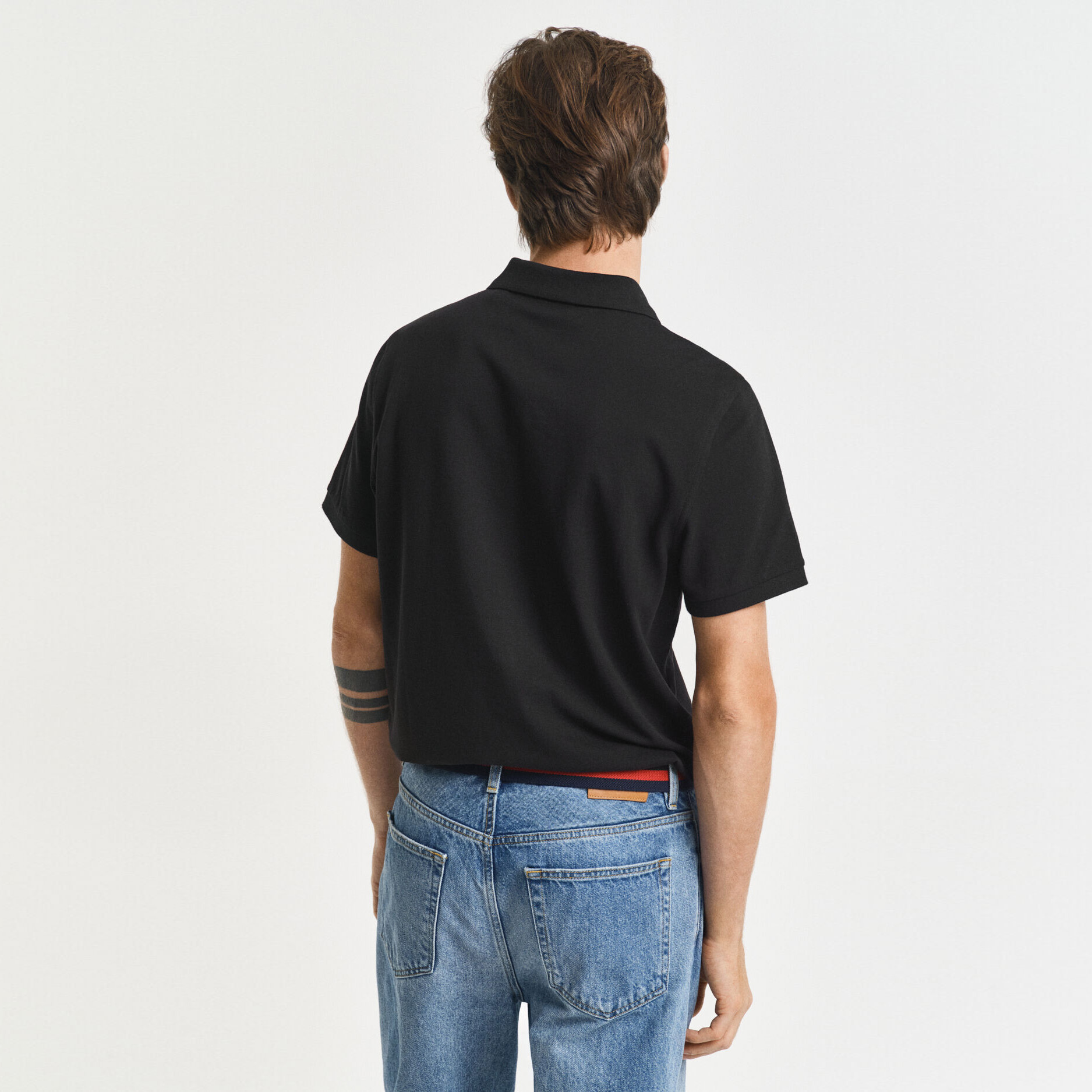 Homem de costas com t-shirt preta e calças de ganga azuis