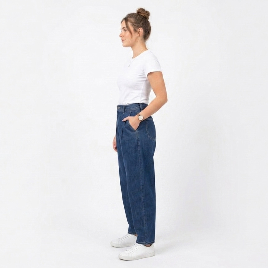 Mulher de perfil com t-shirt branca, jeans azuis largos e ténis brancos