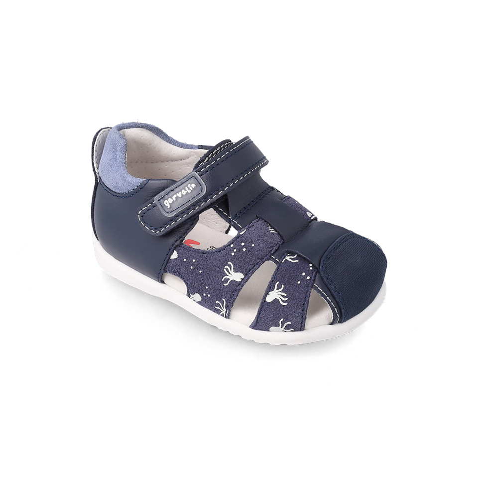 Sandália infantil azul escura com fecho de velcro e padrão de pequenos desenhos brancos.