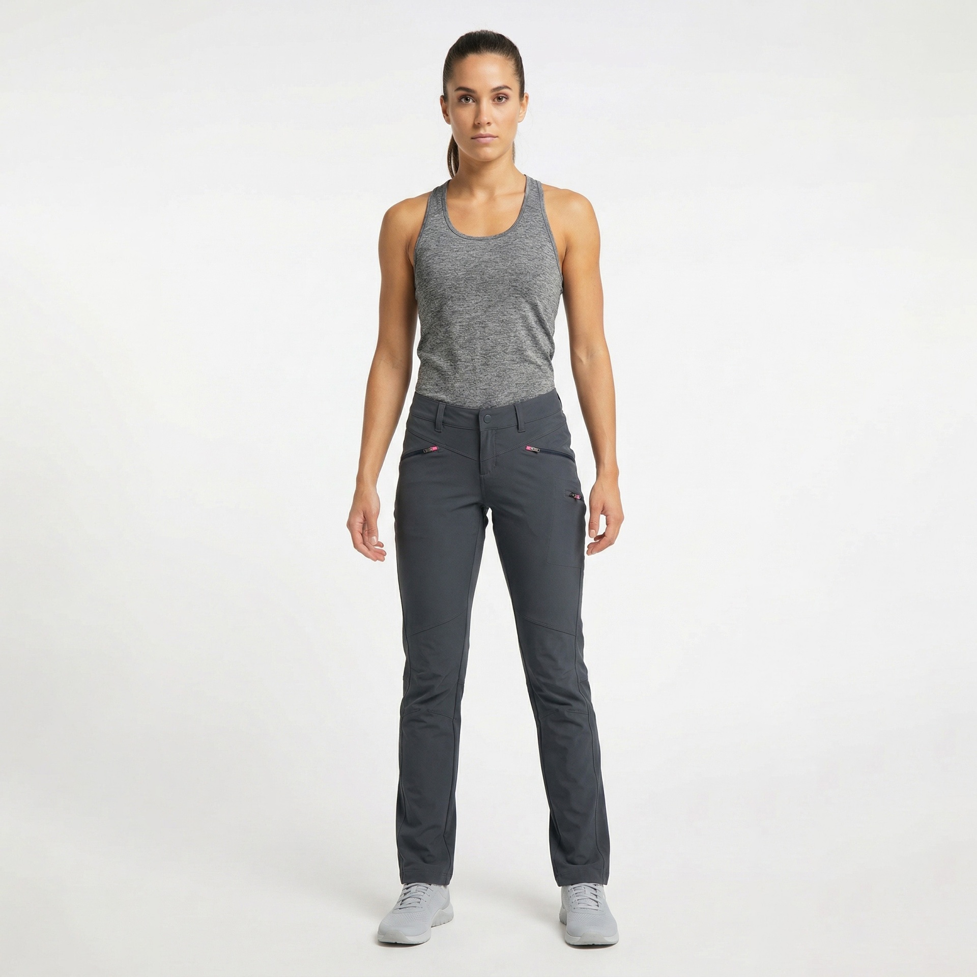 Mulher em pé com roupa desportiva cinza e preta sobre fundo branco.