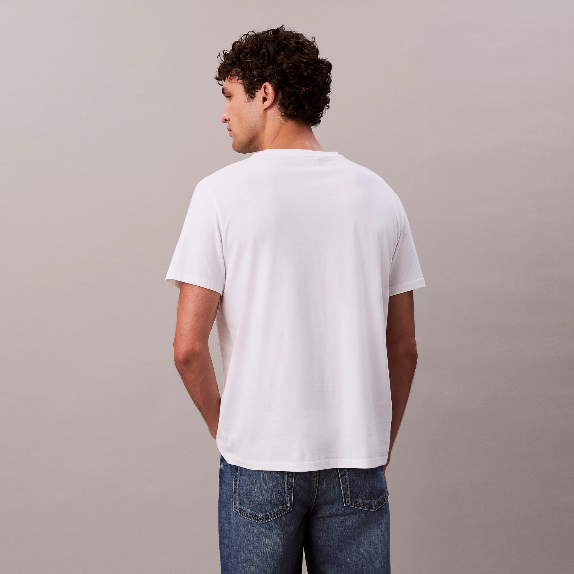 Homem de costas com t-shirt branca e calças de ganga