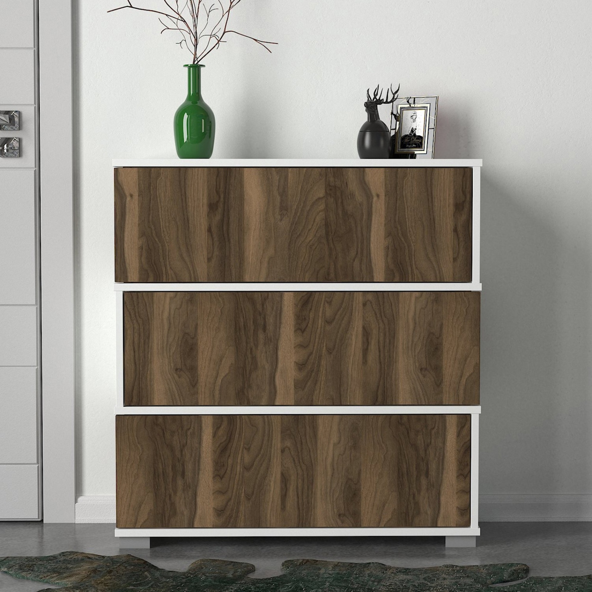 Cómoda branca com frente em madeira castanha decorada com vaso verde e busto de cervo preto com porta-fotos.