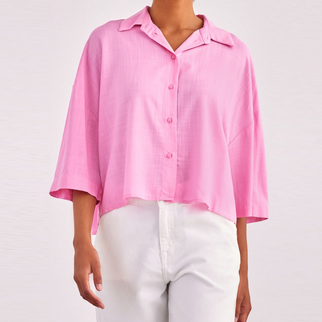 Camisa rosa de tecido leve com botões e gola, usada com calças brancas