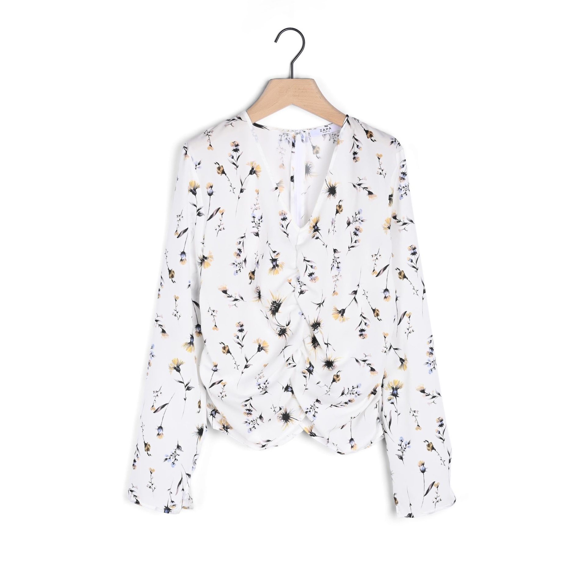 Blusa feminina branca com padrão floral e detalhe franzido pendurada num cabide