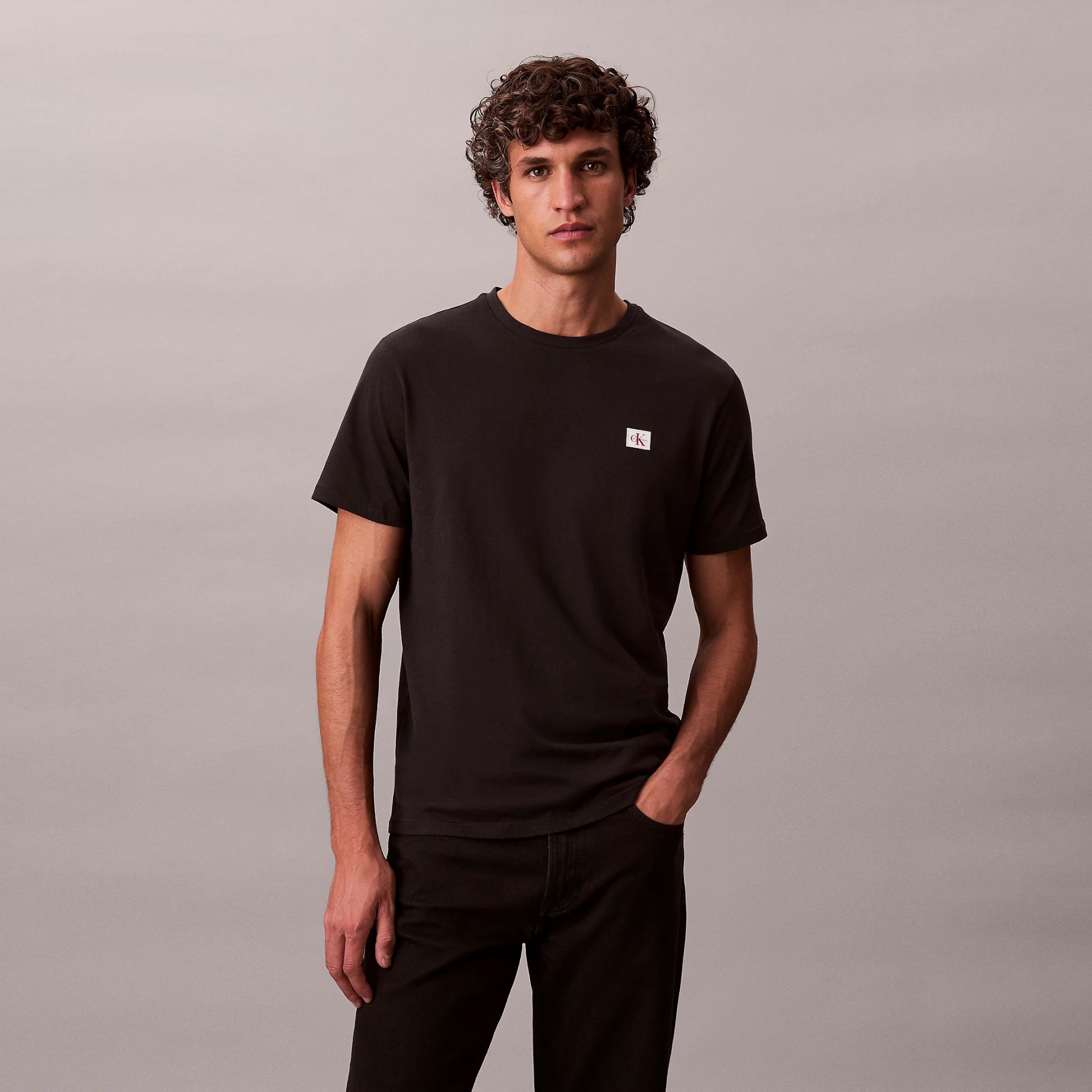 Homem com t-shirt preta e logótipo cK e calças pretas