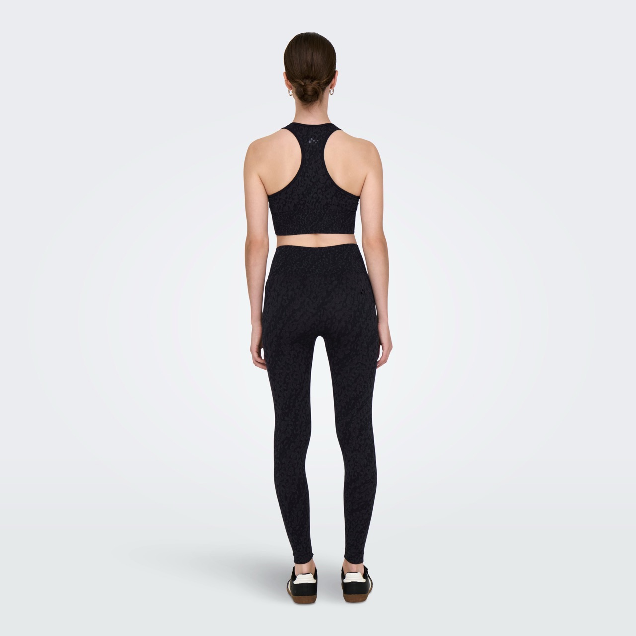 Mulher de costas usando conjunto desportivo preto com textura padrão