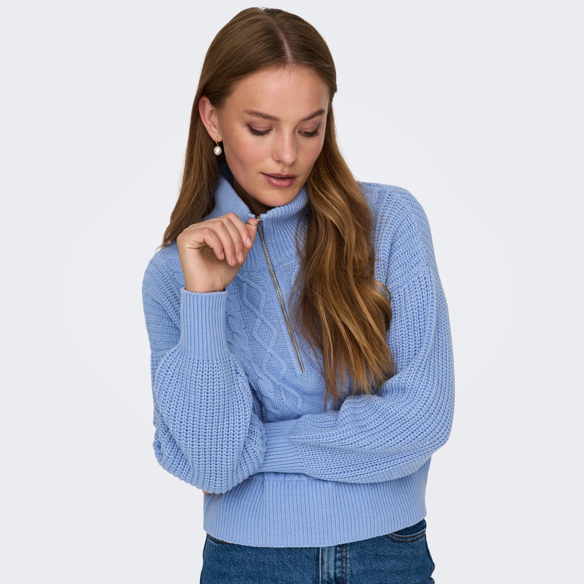 Mulher a usar camisola azul clara de malha com gola alta e fecho de correr