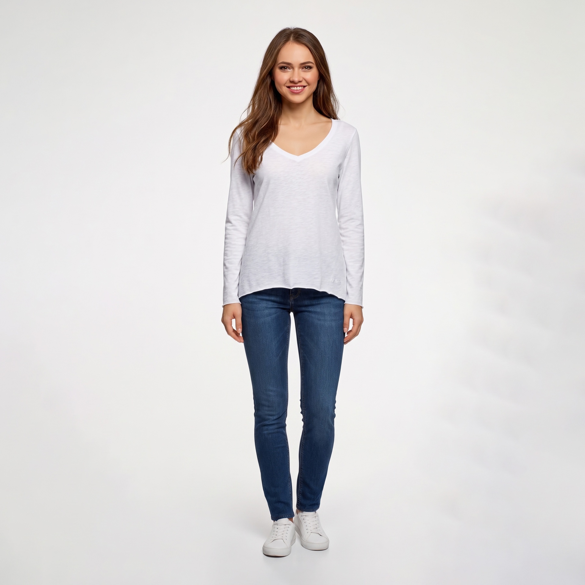 Mulher com camisola branca de manga comprida, jeans azuis e ténis brancos