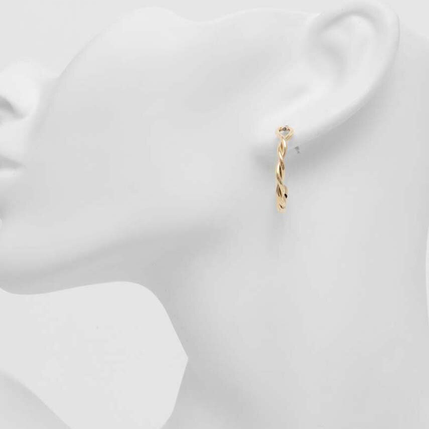 Brinco de argola dourado torcido no ouvido de manequim branco