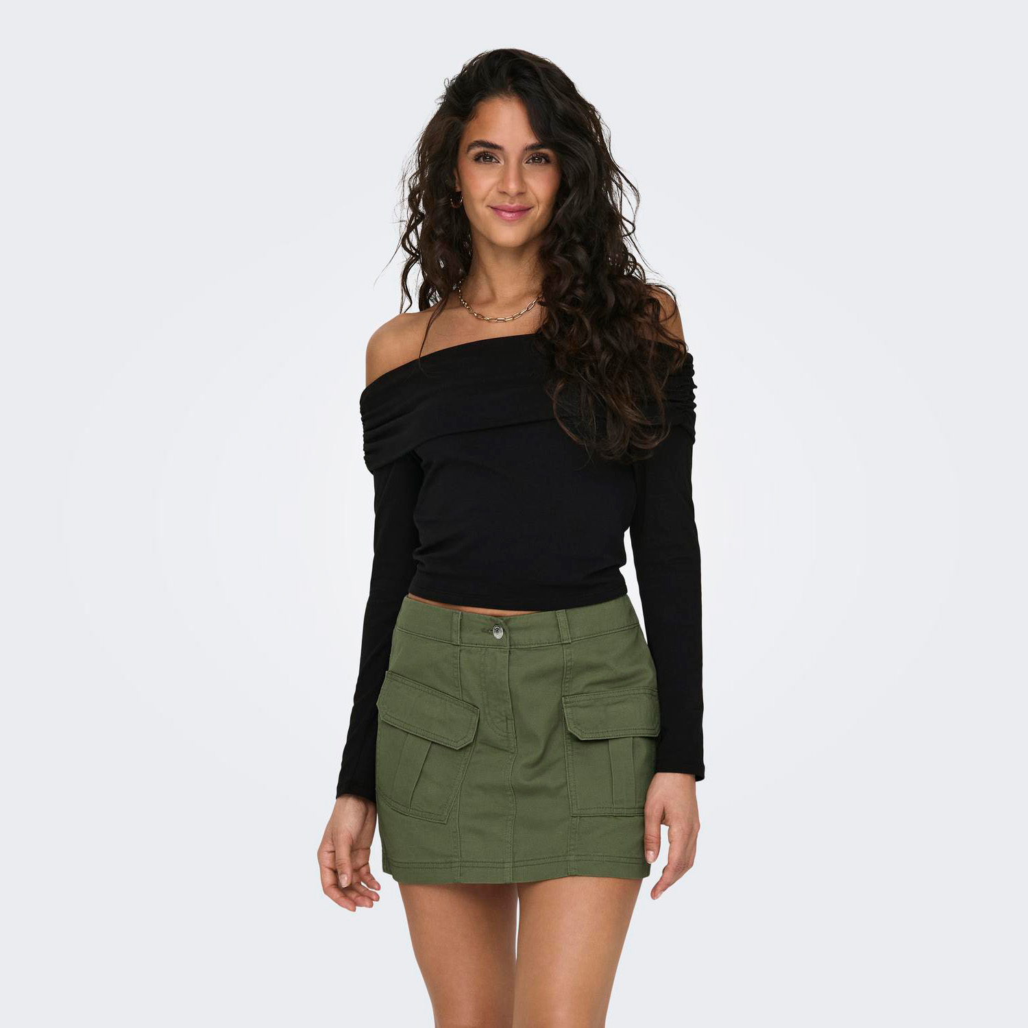 Mulher com top preto ombro a ombro e saia verde com bolsos