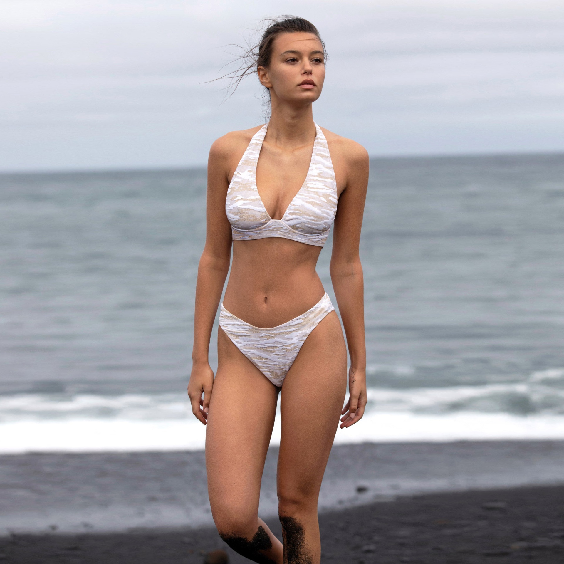 Mulher com biquíni branco texturizado na praia com mar ao fundo