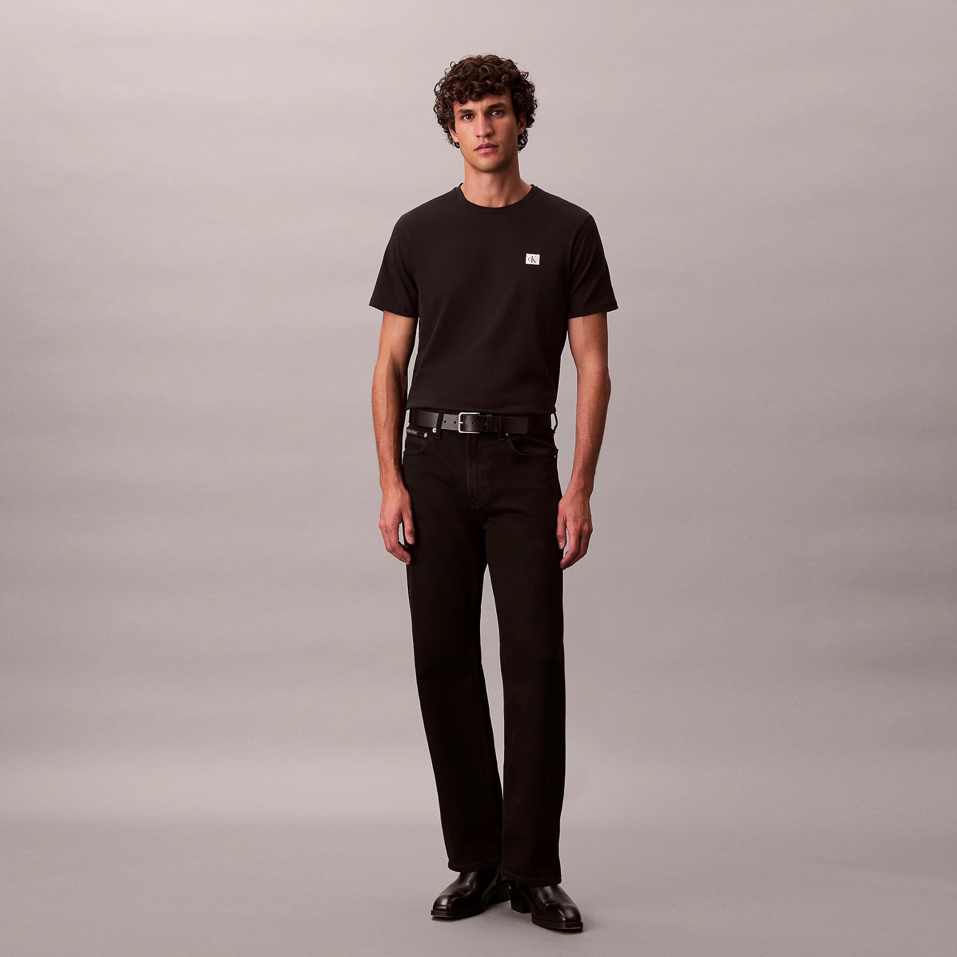 Homem com roupa preta em fundo cinzento claro