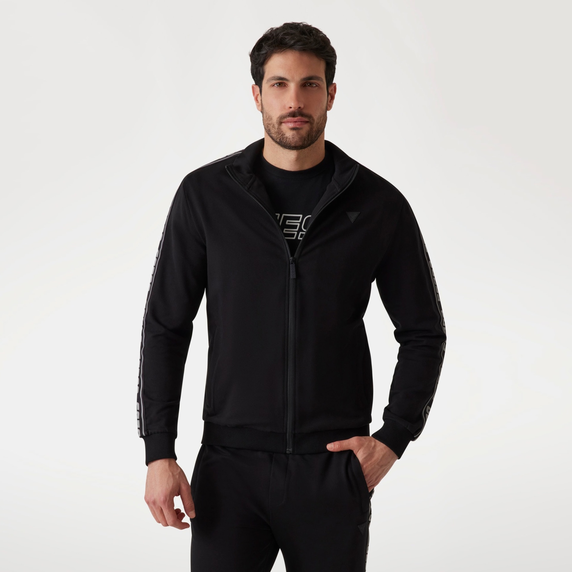 Homem a usar casaco desportivo preto com fecho e detalhe branco nas mangas