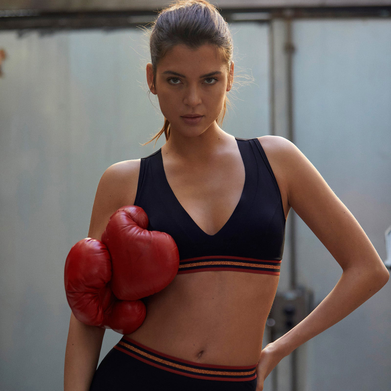 Mulher com luvas de boxe vermelhas e roupa desportiva preta