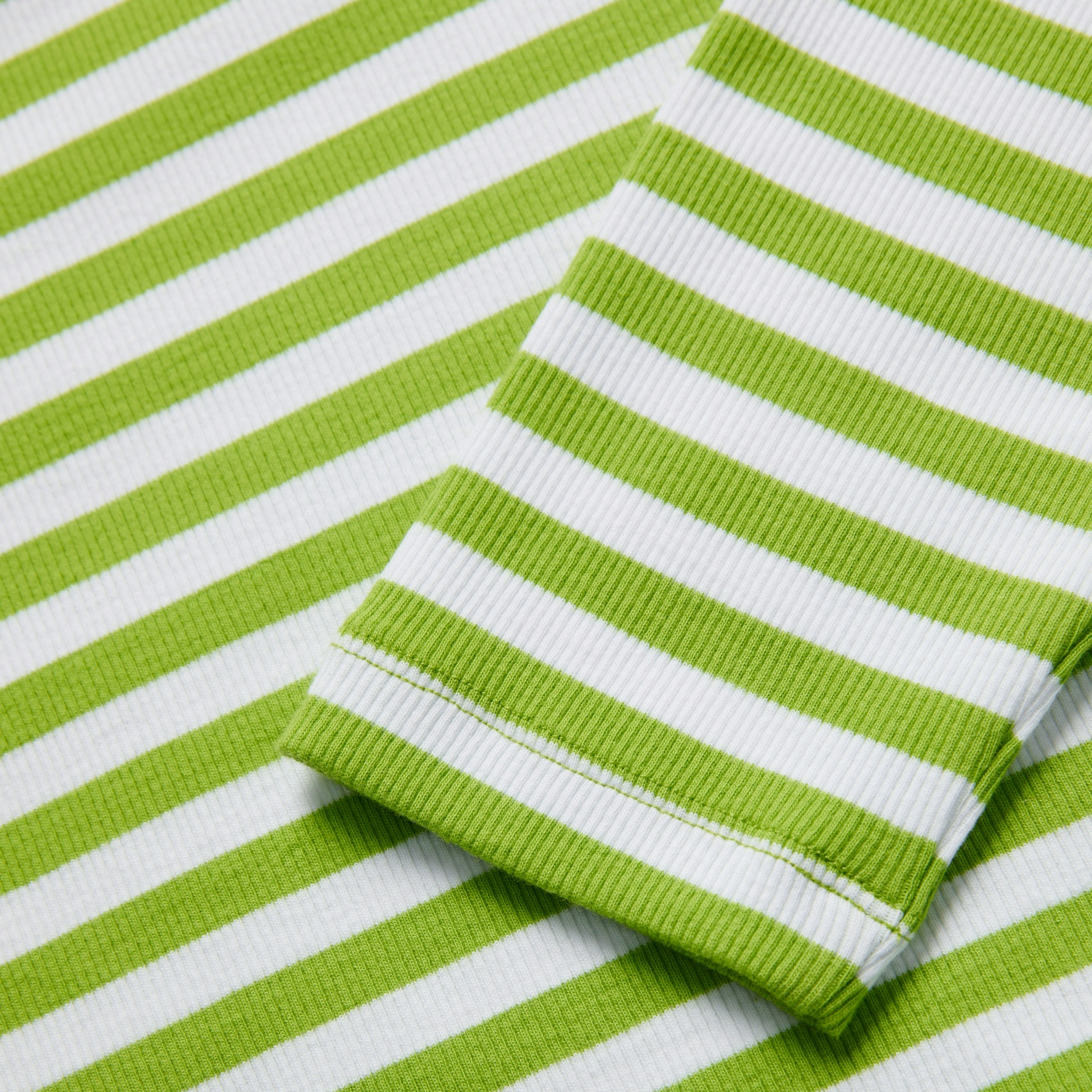 Tecido canelado de algodão com riscas verdes e brancas em formato horizontal.