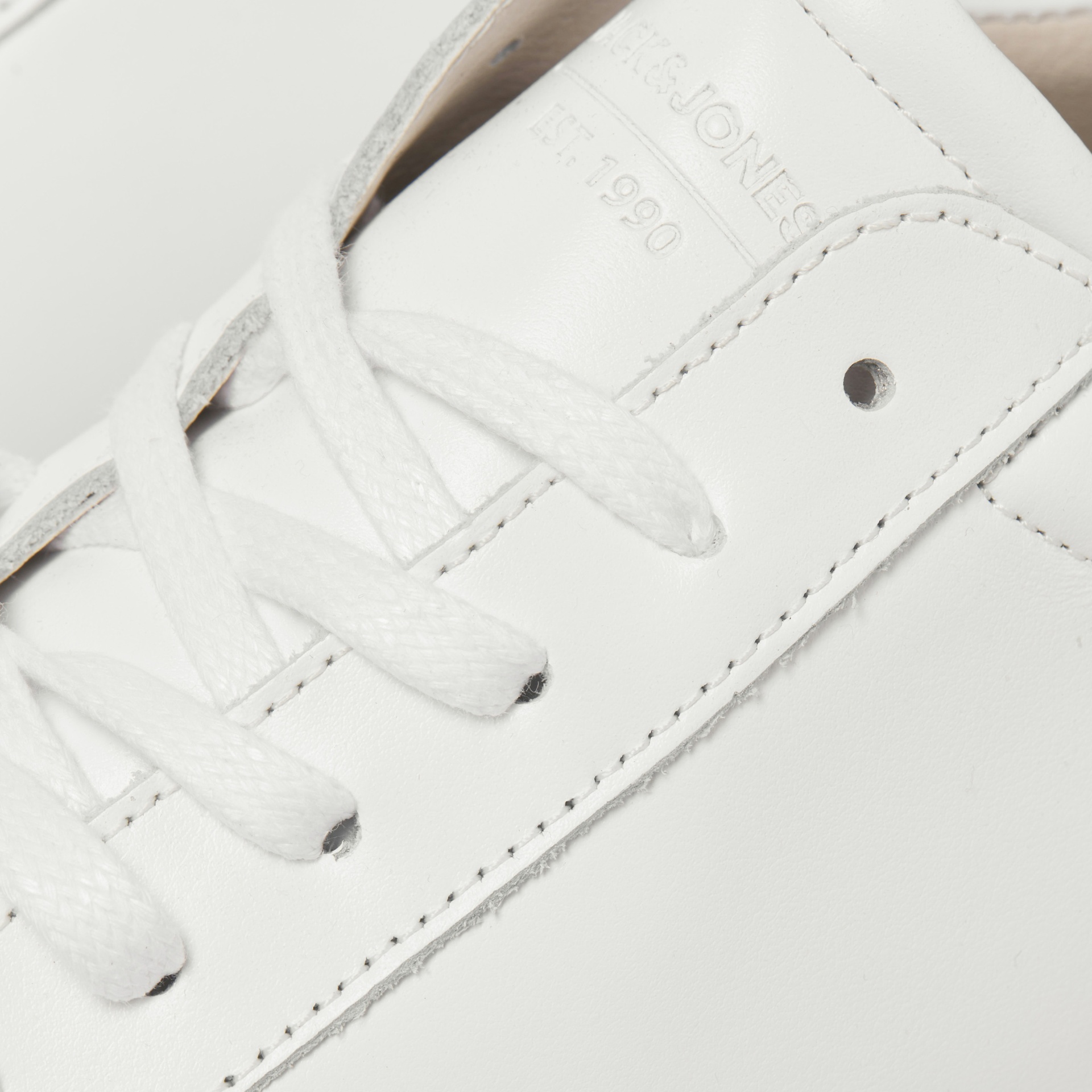 Sapatilha branca em pele com atacadores brancos e texto JACK & JONES Est. 1990 em relevo