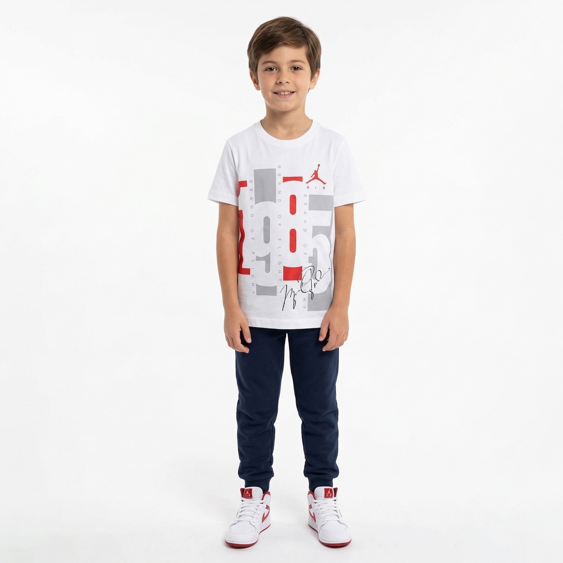 criança com camiseta branca estampada, calças azuis e ténis brancos vermelhos