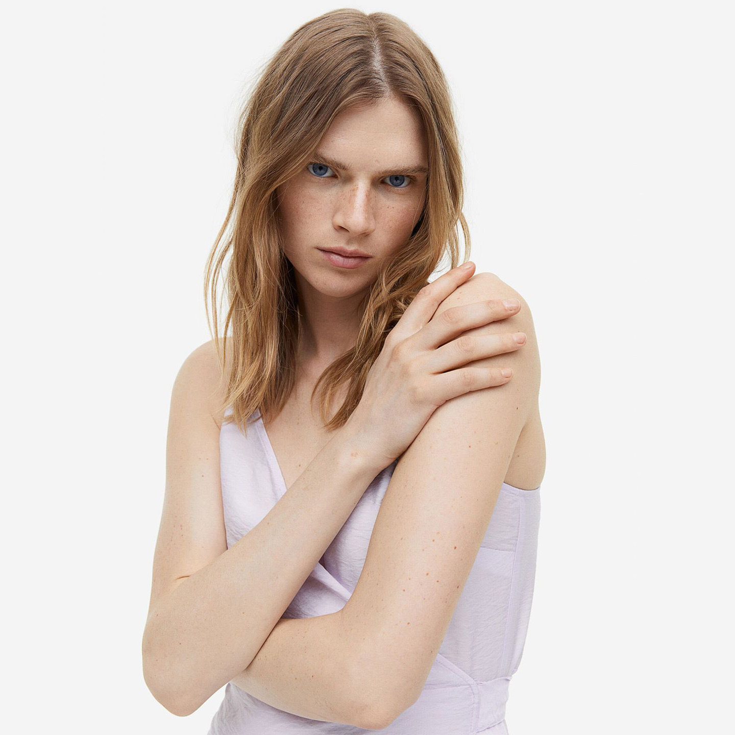 Mulher com vestido lilás e cabelo louro em fundo branco