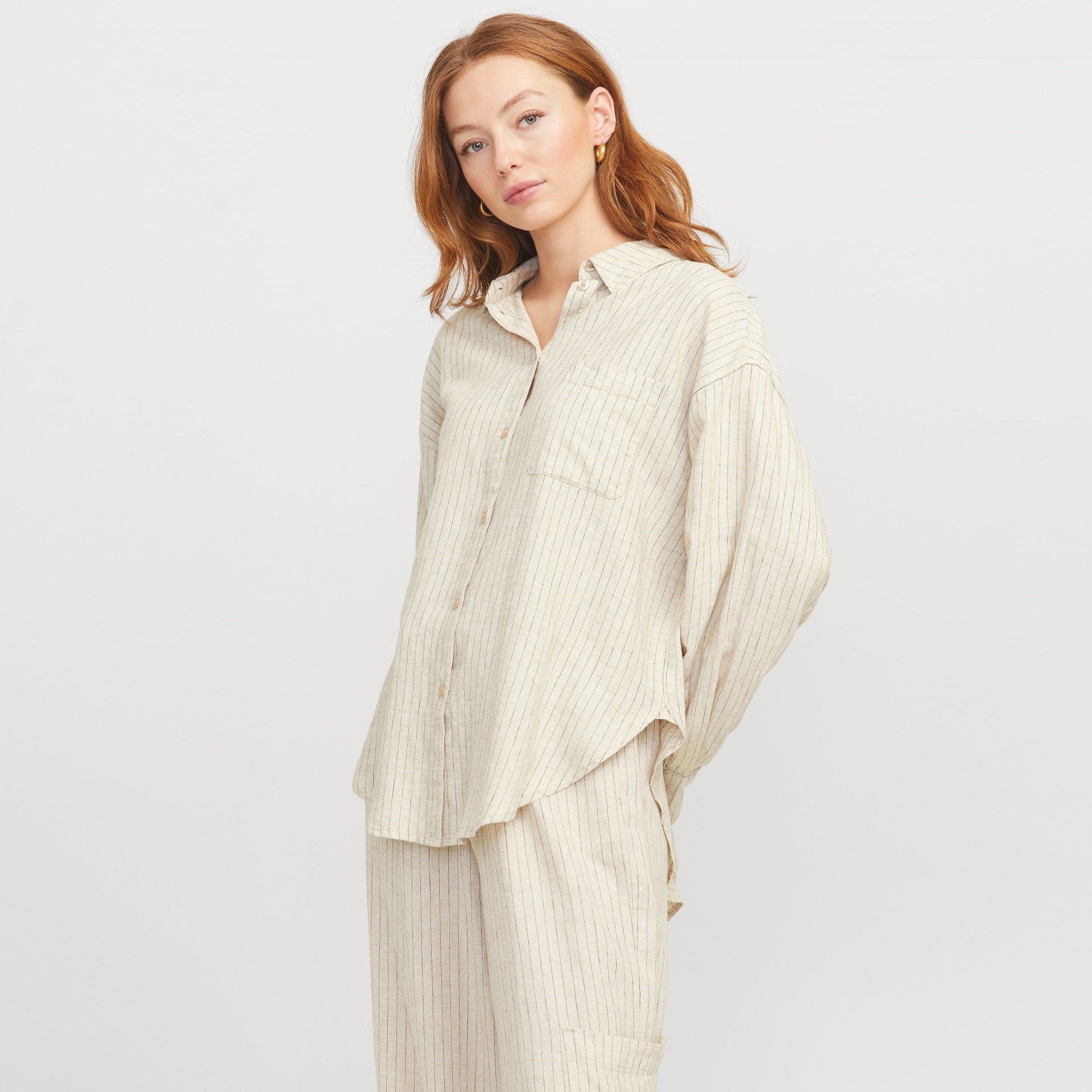 Mulher com pijama riscado bege em fundo branco