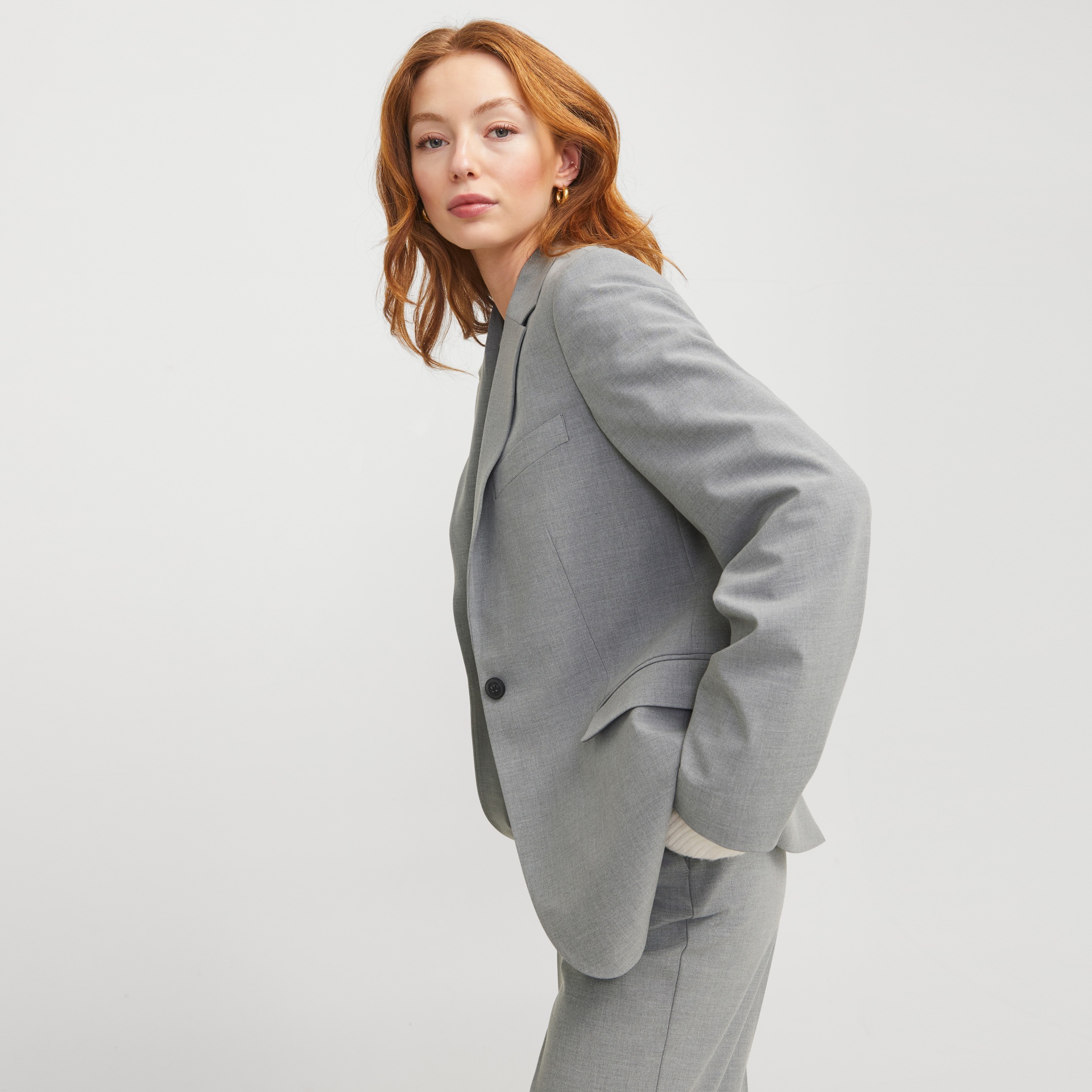 Blazer cinza claro com um botão preto usado por mulher ruiva