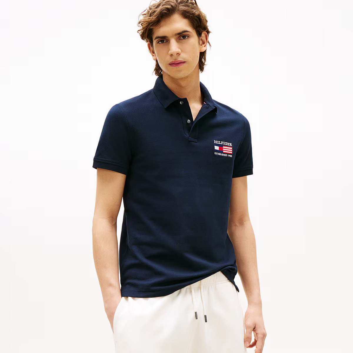 Polo azul escuro com bordado Hilfiger e calças brancas