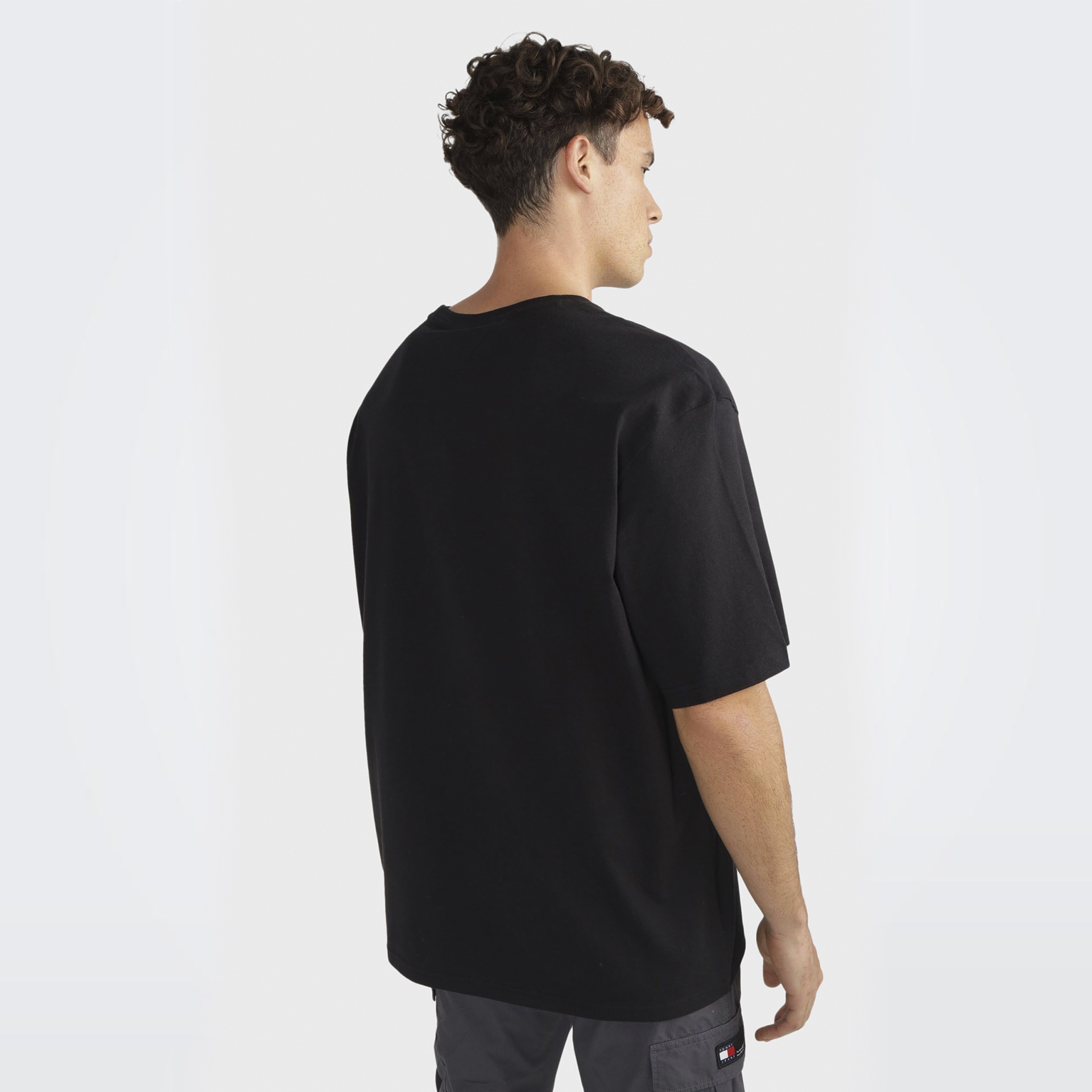 Homem de costas com t-shirt preta de manga curta e calças cinzentas