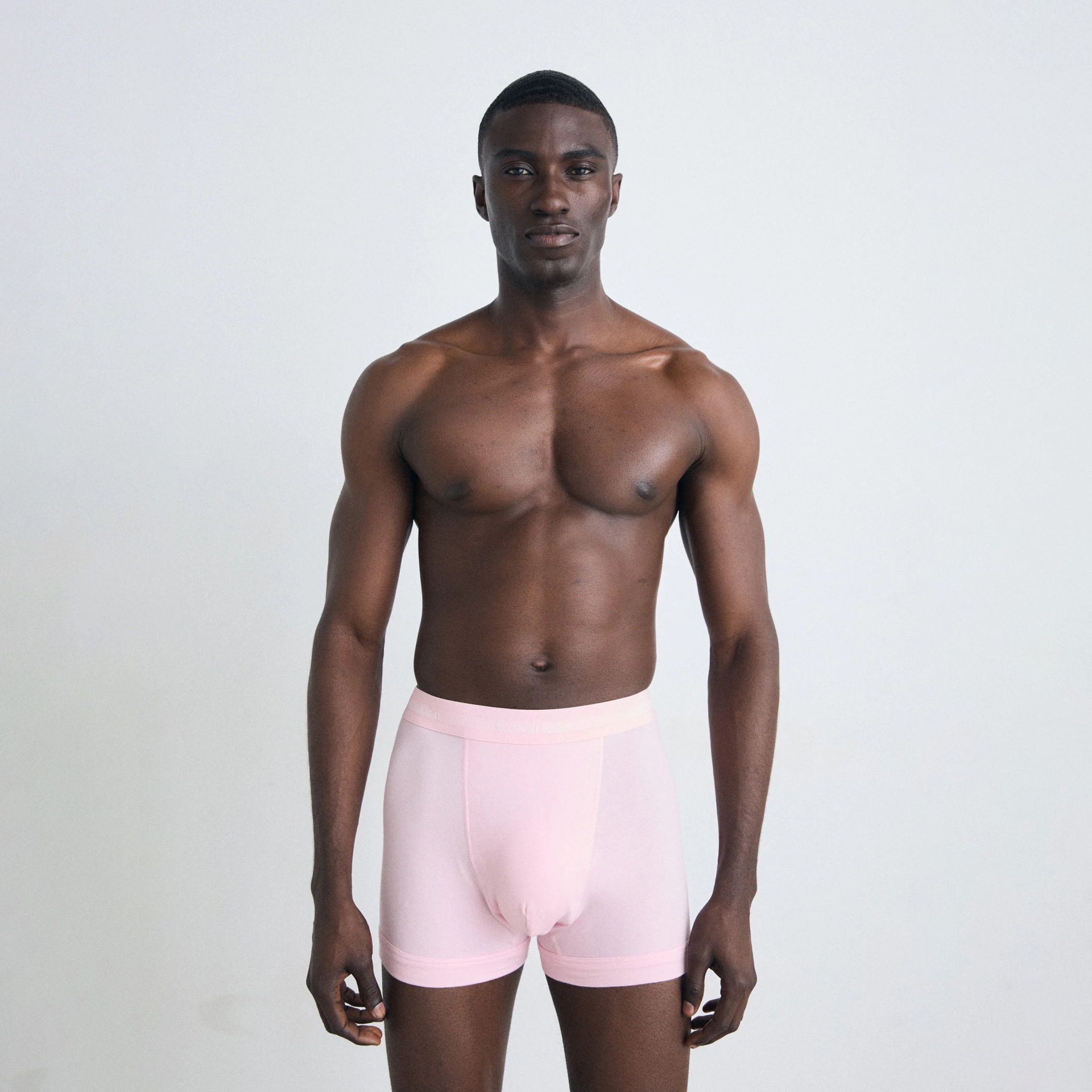 Homem com boxers cor-de-rosa claro em fundo branco