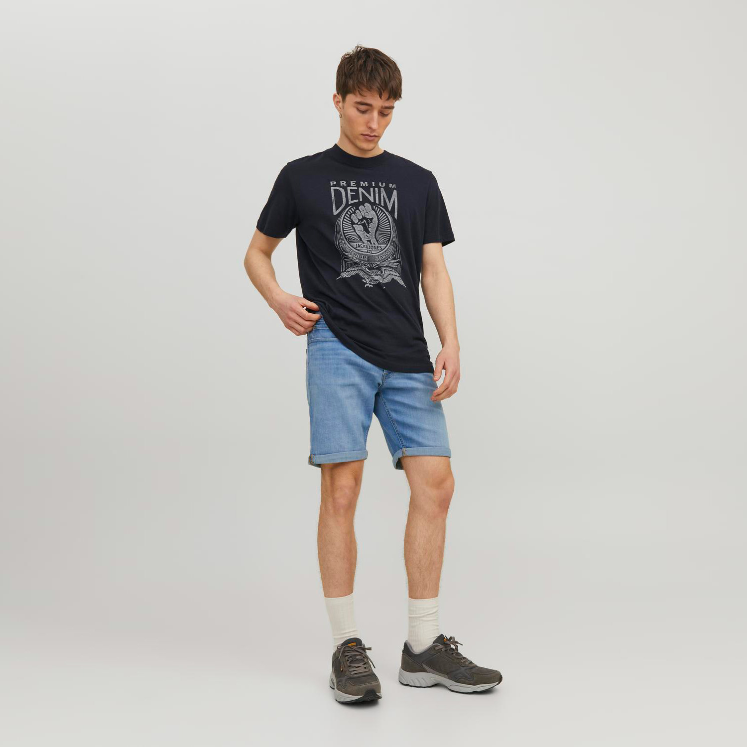 Homem com t-shirt preta com estampa DENIM e calções de ganga azuis claros