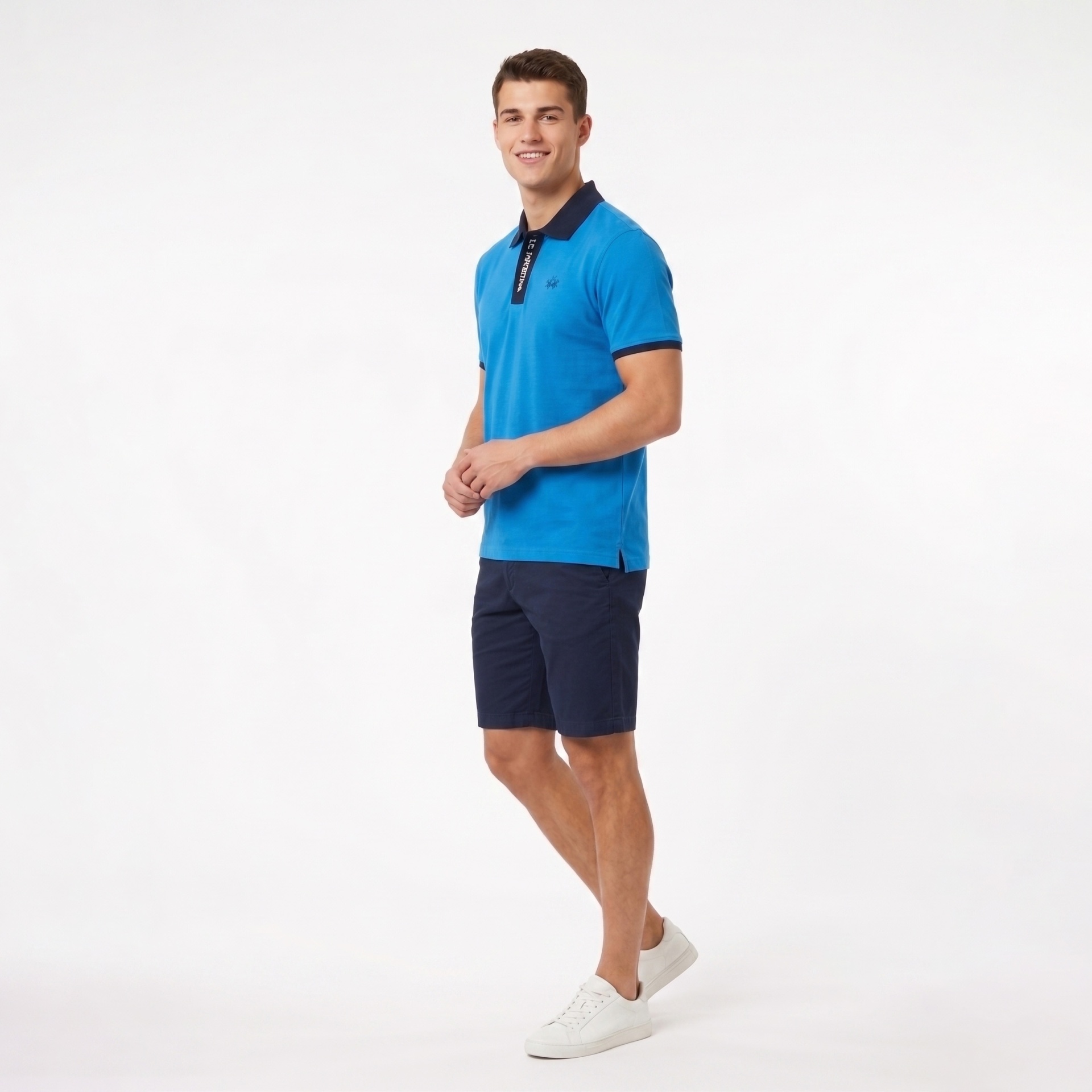 Homem com polo azul e calções azuis escuros em fundo branco