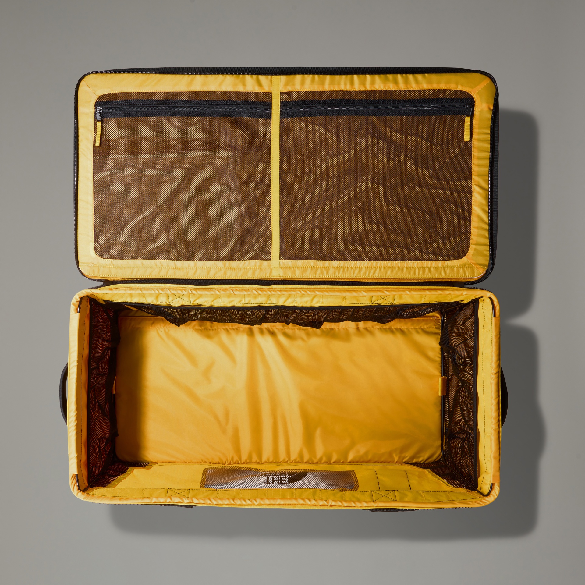 Mala de viagem aberta com interior amarelo e compartimentos em rede preta.