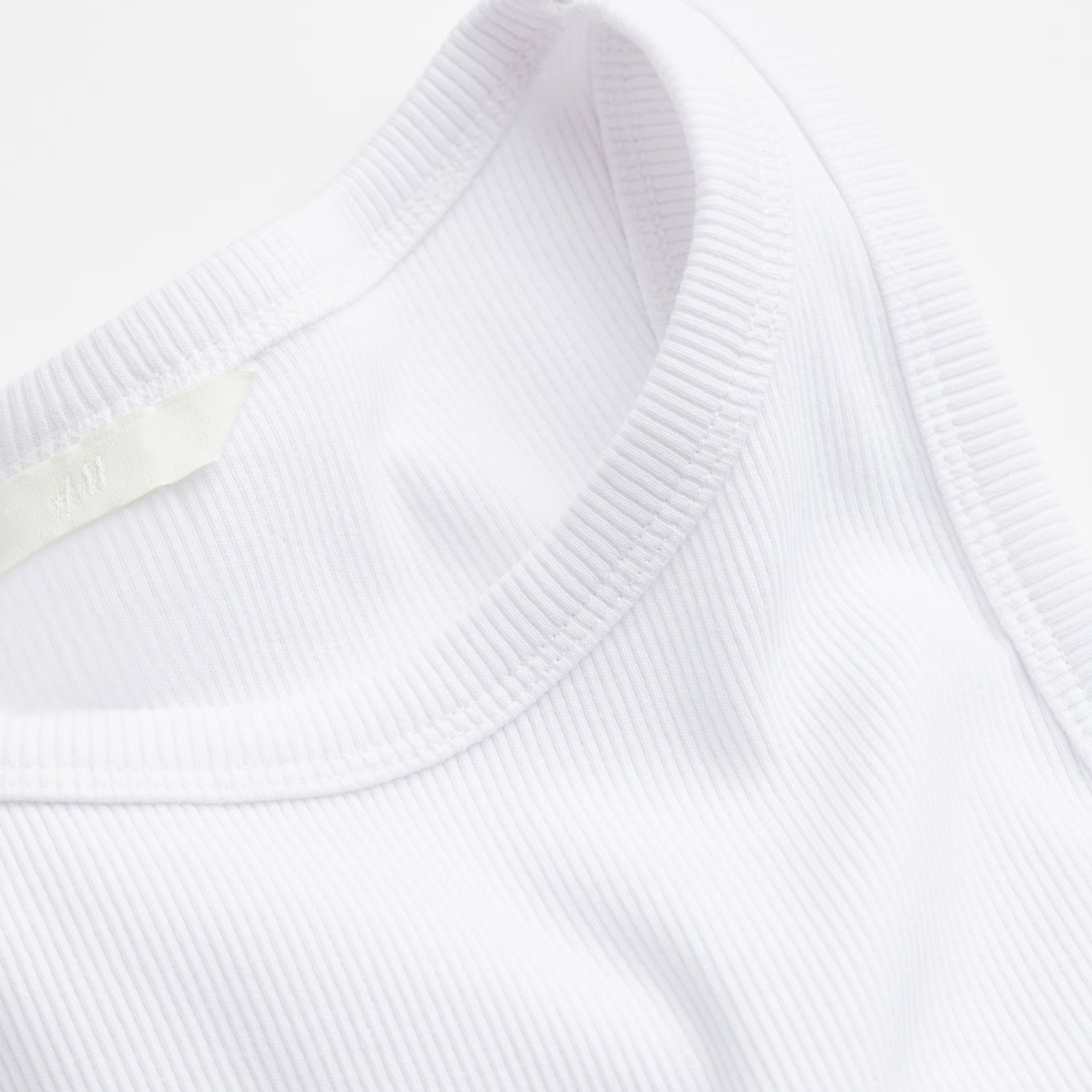 Camisola branca de tecido canelado com gola redonda e etiqueta interior