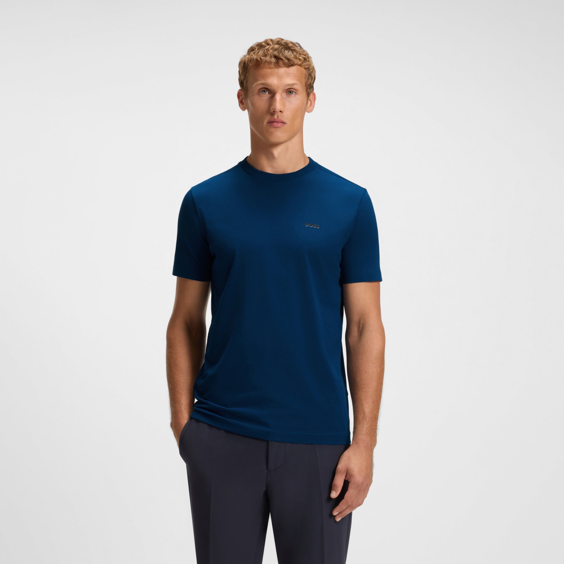 Homem a usar t-shirt azul escura BOSS com gola redonda e calças escuras