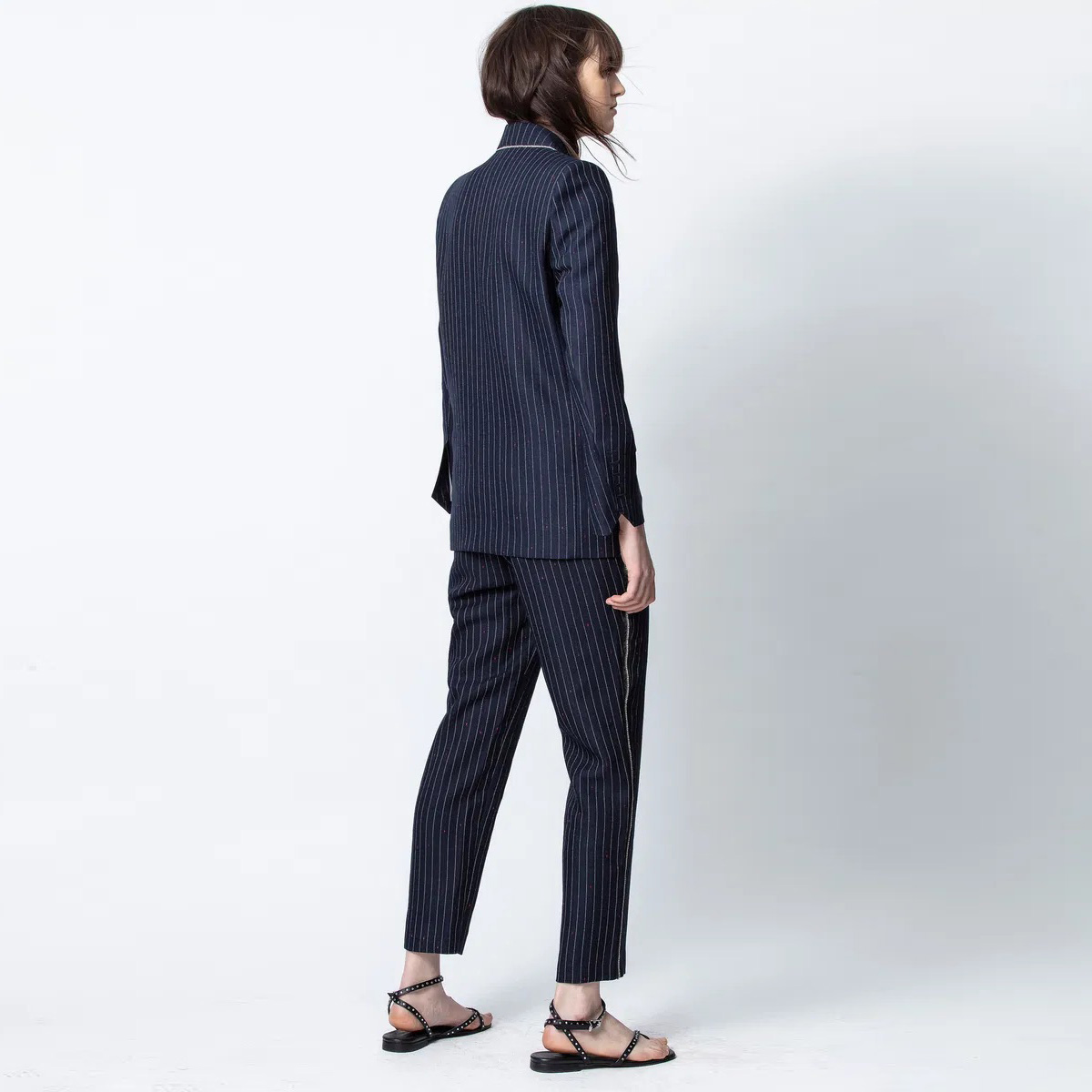 Mulher de costas a usar fato riscado azul escuro e sandálias pretas