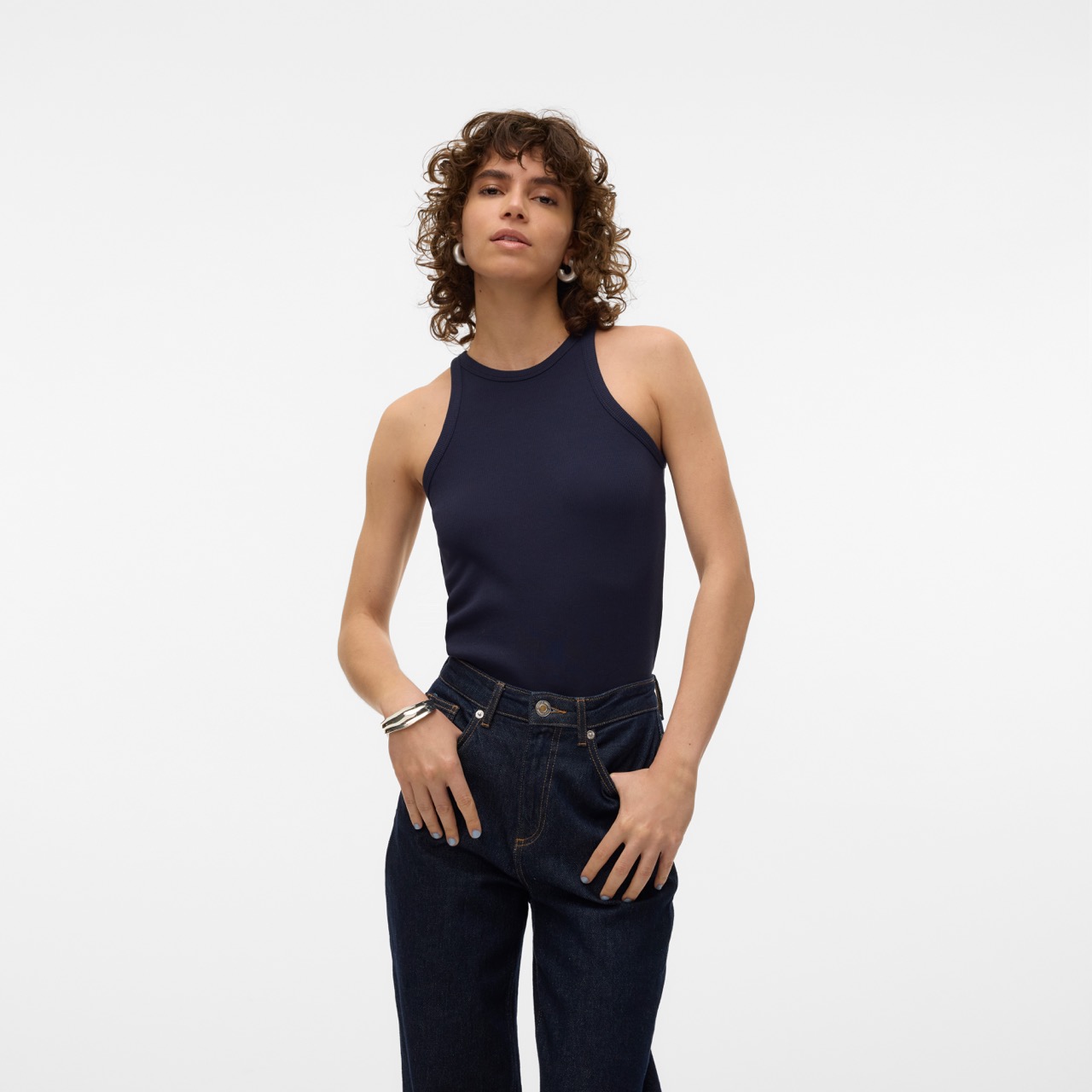 Mulher com camisola azul escura sem mangas e calças de ganga azul escuro