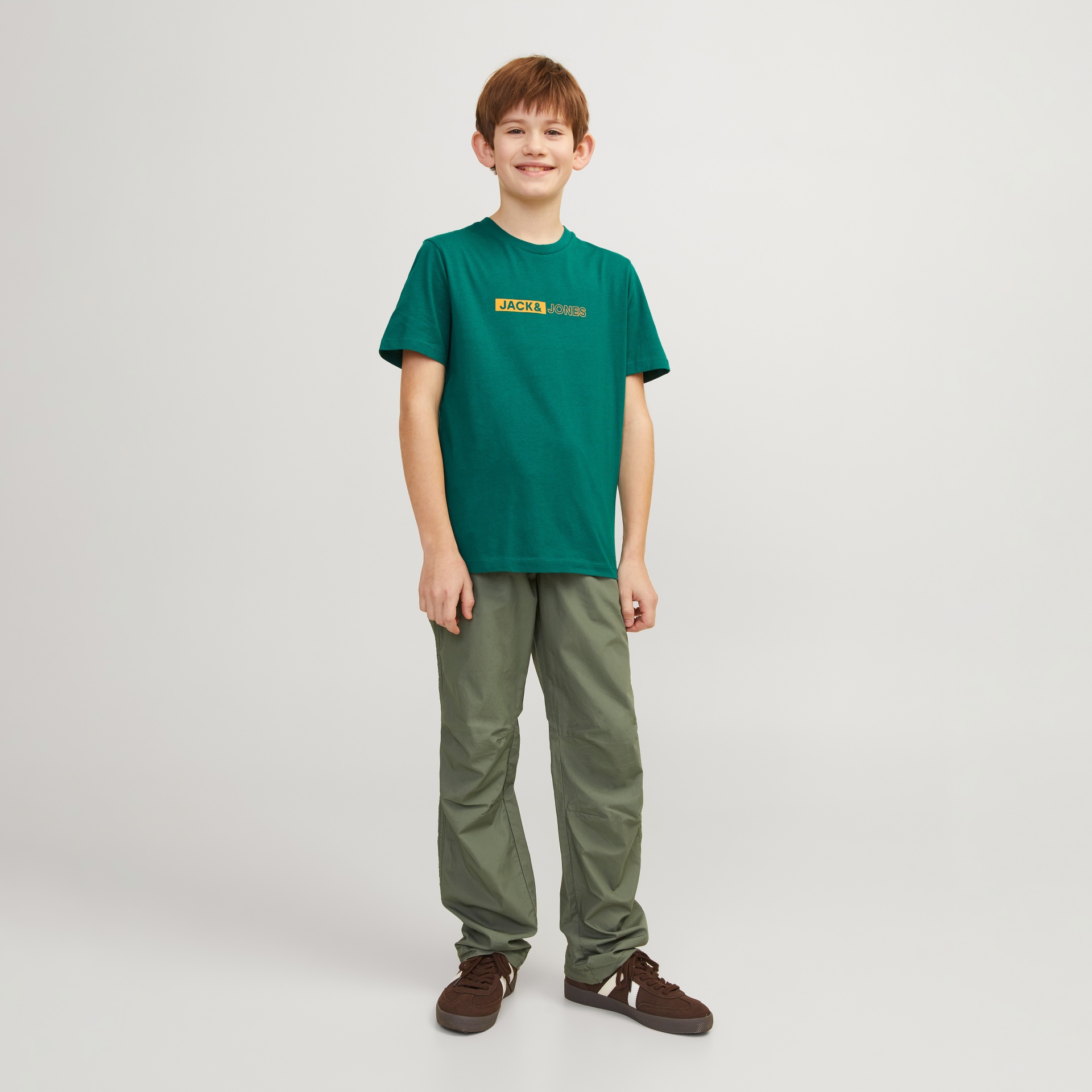 Rapaz com t-shirt verde Jack & Jones e calças verdes com ténis castanhos
