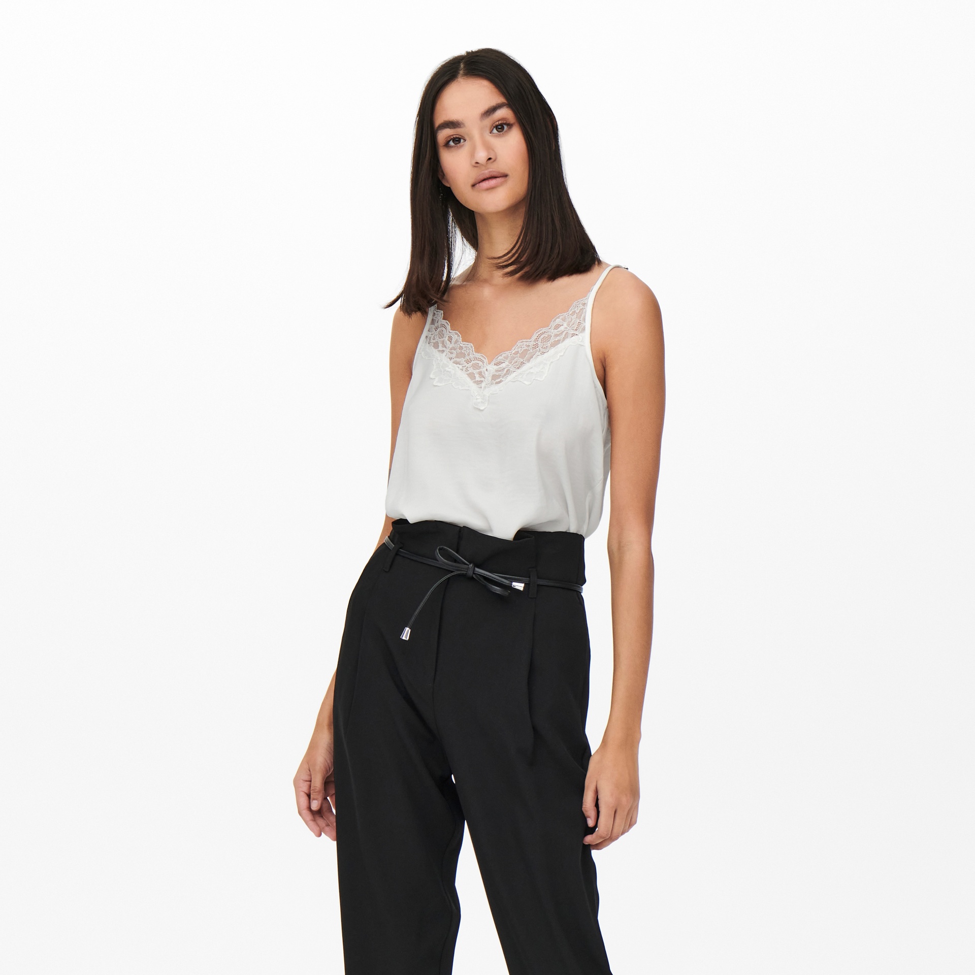 Mulher vestindo top branco com renda e calças pretas com cinto